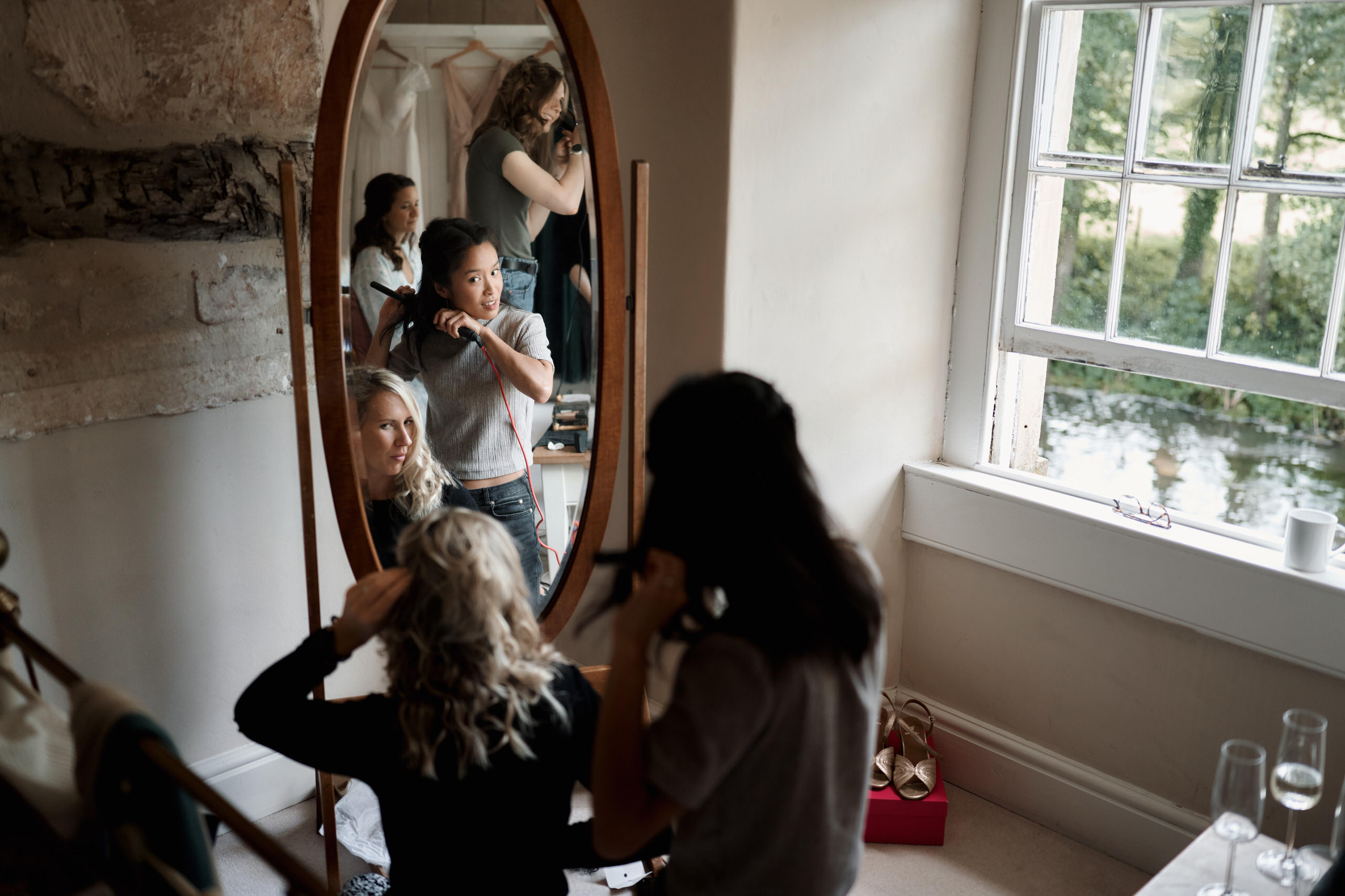 A woman is having her hair styled before her wedding, while looking at herself in the mirror.