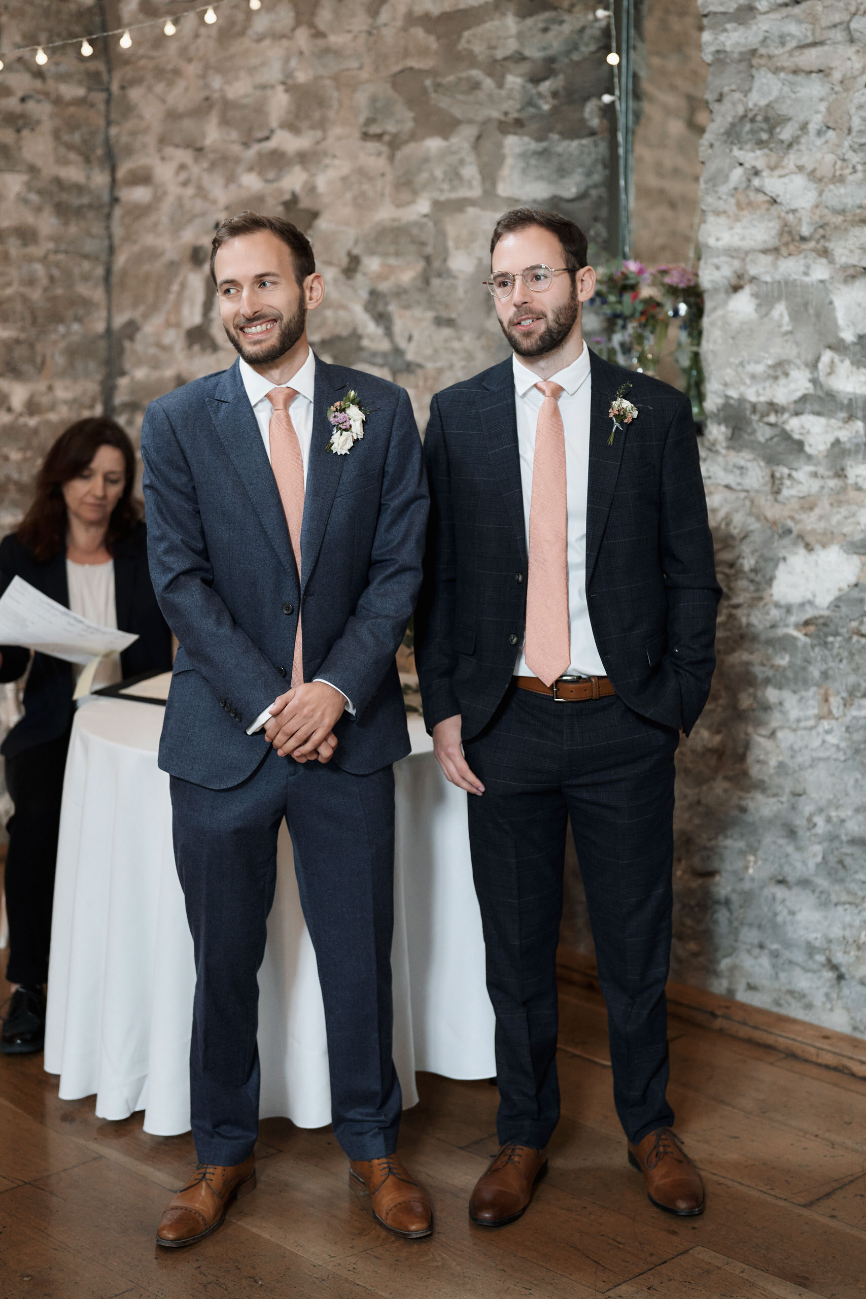 Two guys in suits are standing beside each other.
