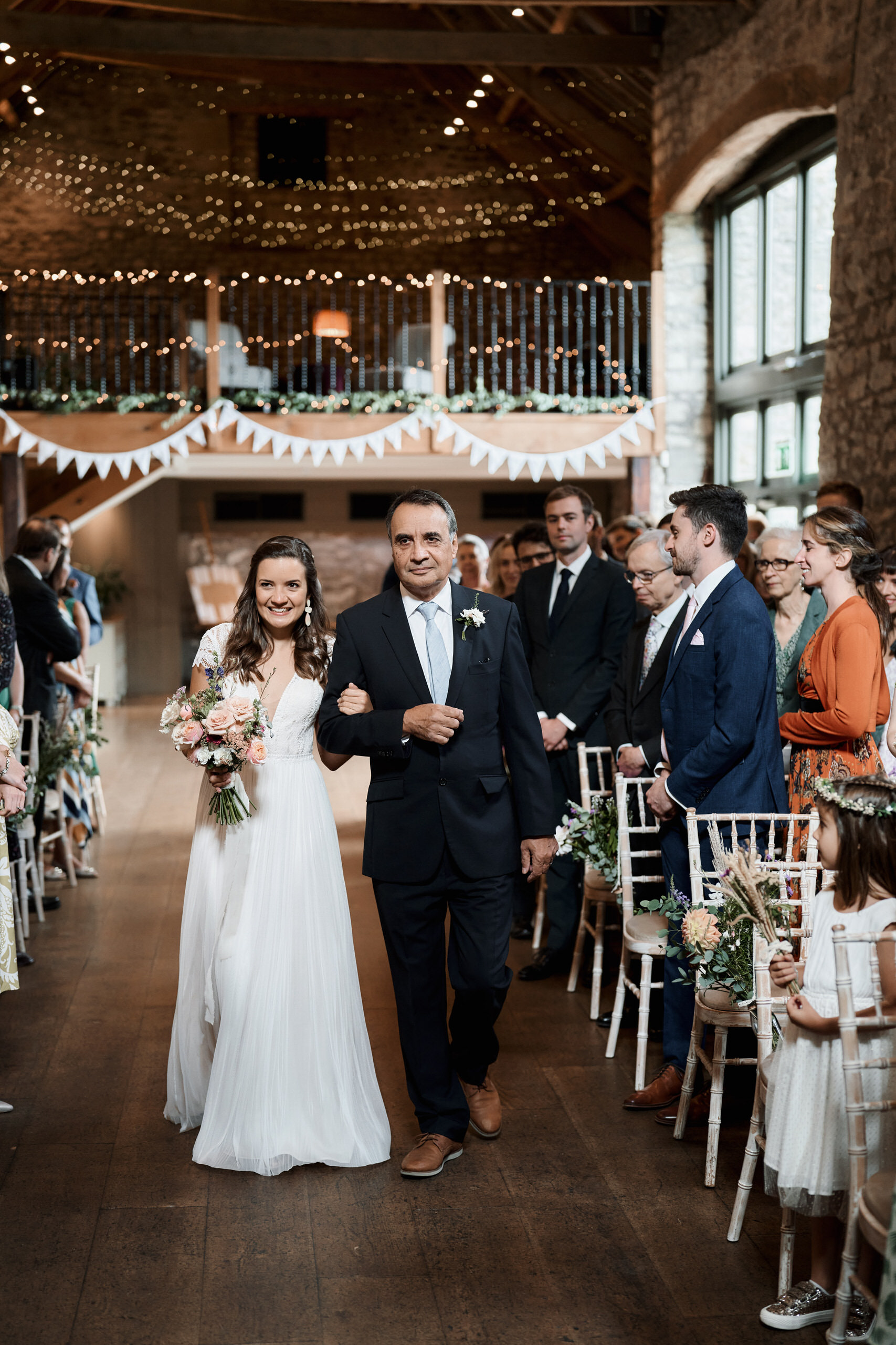 A couple is walking down the aisle at a farm-style wedding.