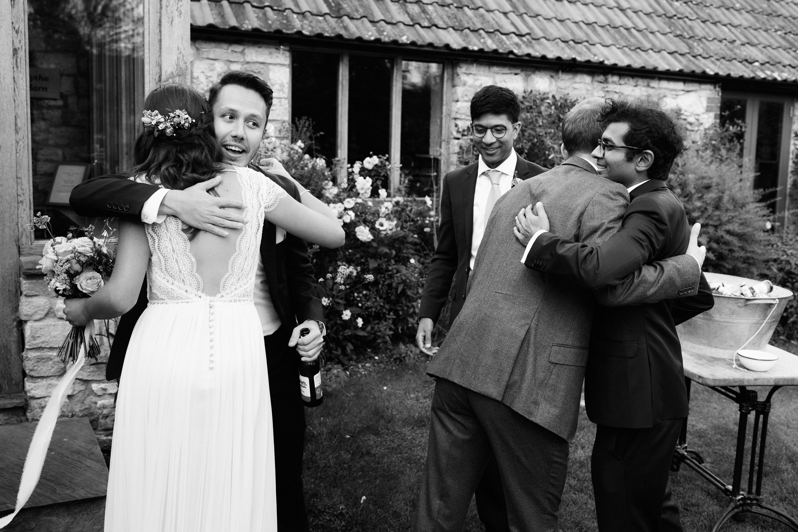 A black and white picture of a bride giving her bridesmaids a tight hug.
