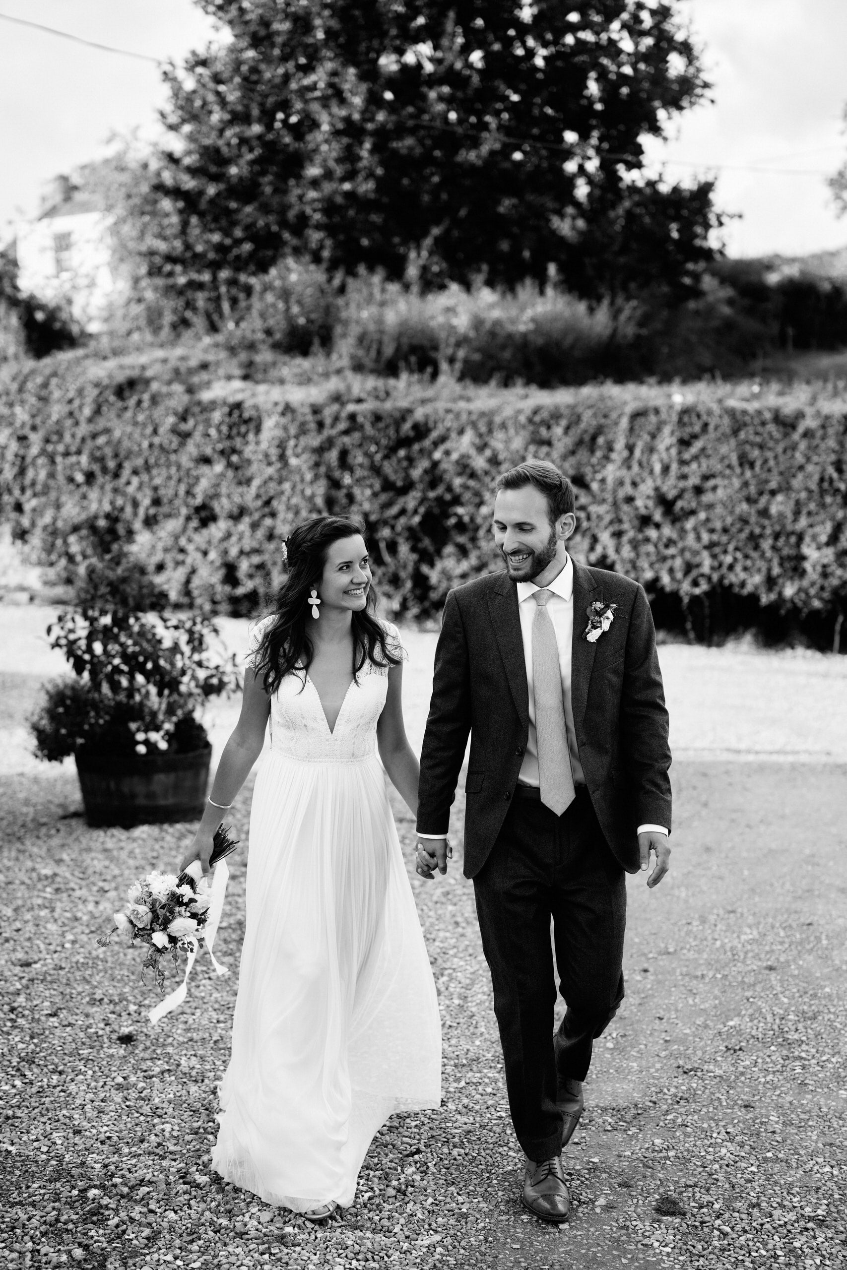 A black and white picture of a newly married couple walking down a path.