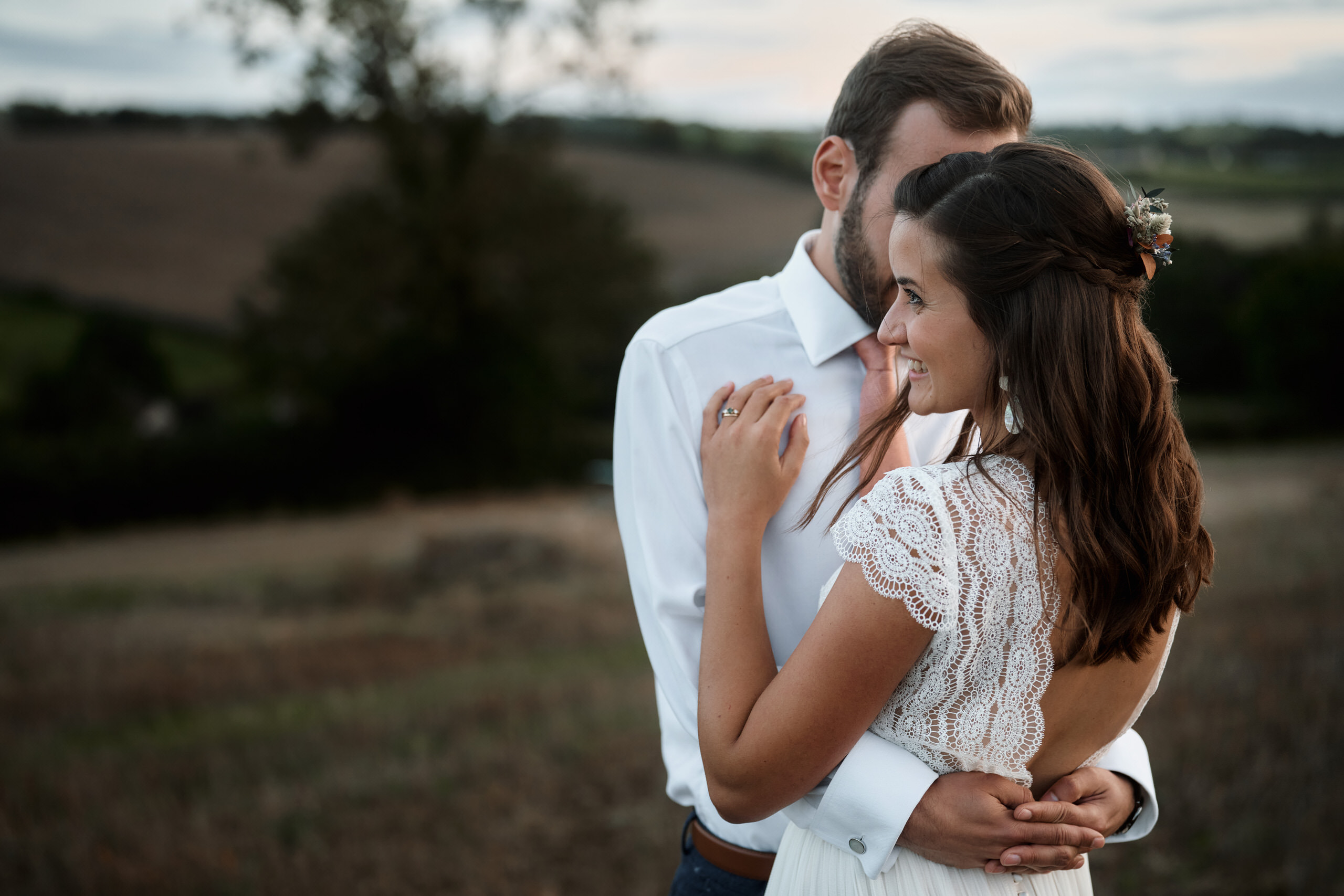 A couple getting married is hugging in a field.