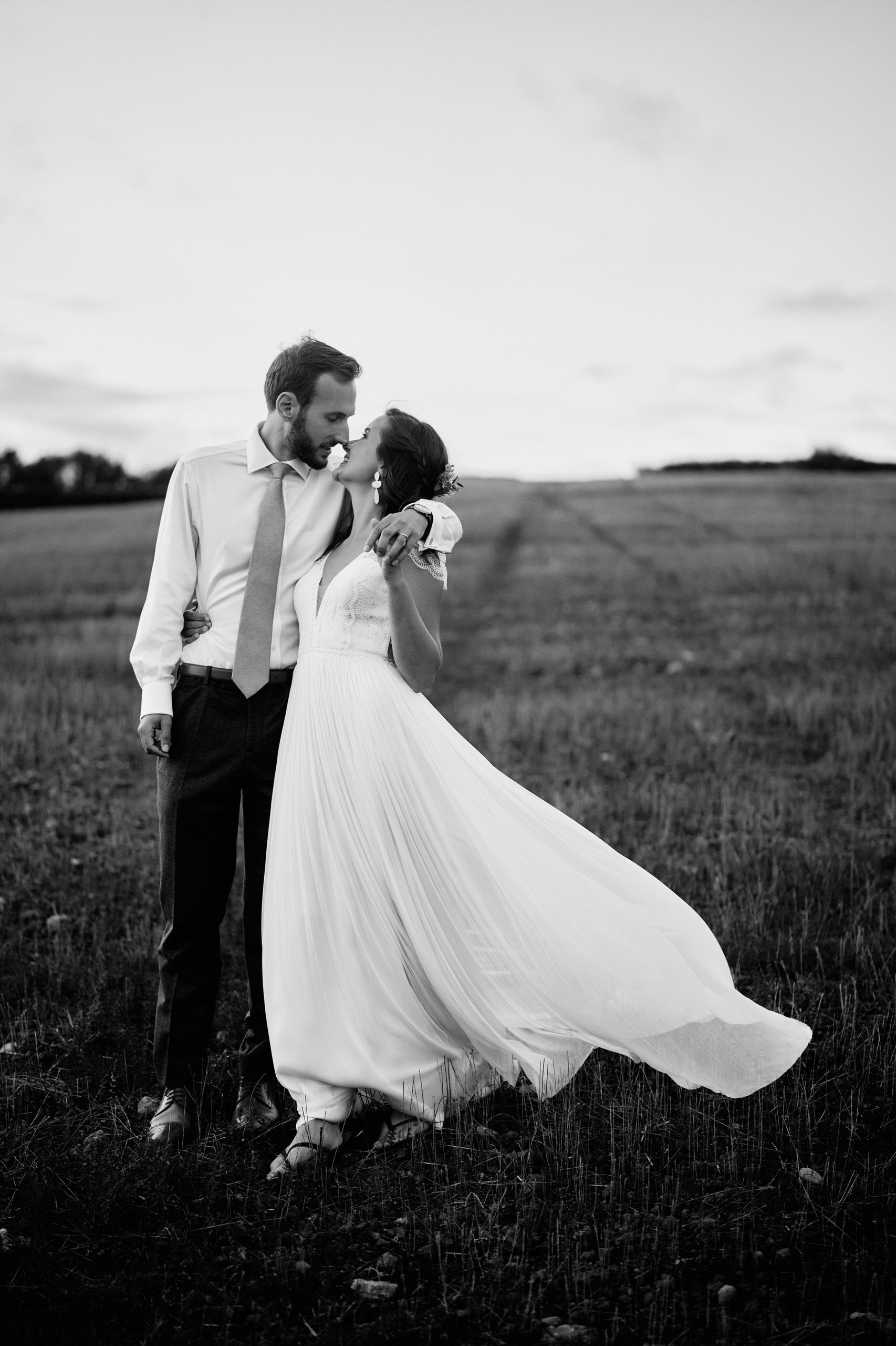A couple getting married are kissing in a field.