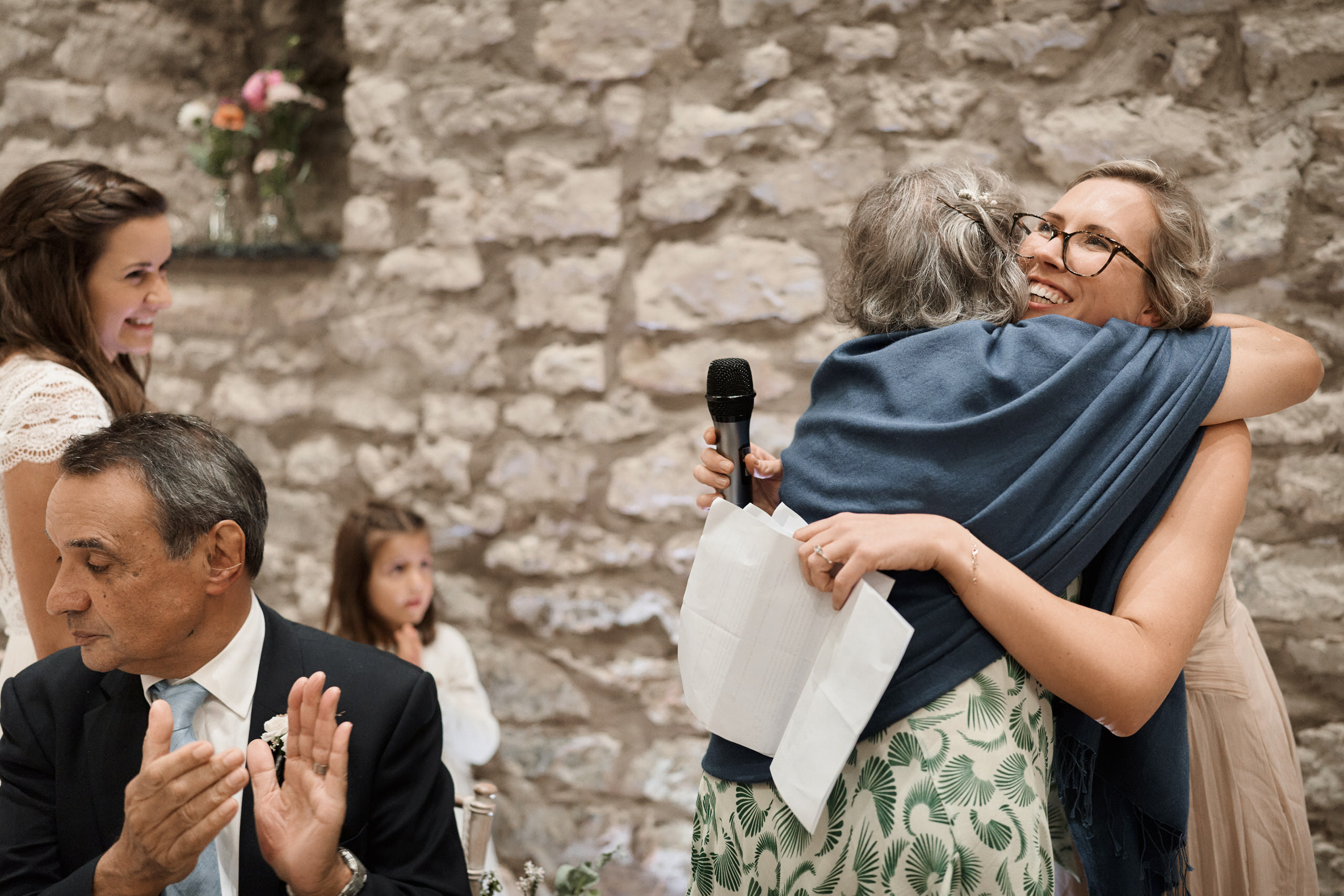 At a wedding, the bride is giving her mom a hug.