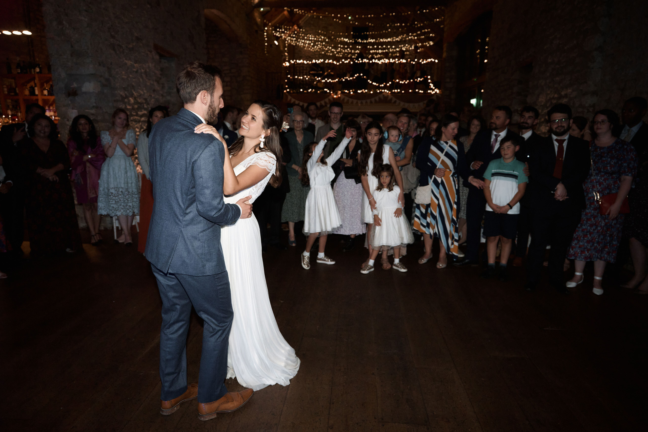 A couple is having their first dance in a barn after getting married.