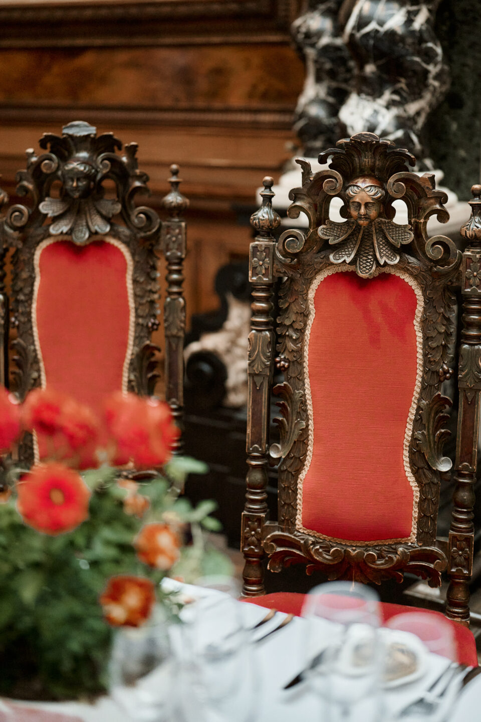 A fancy table with red chairs and flowers.
