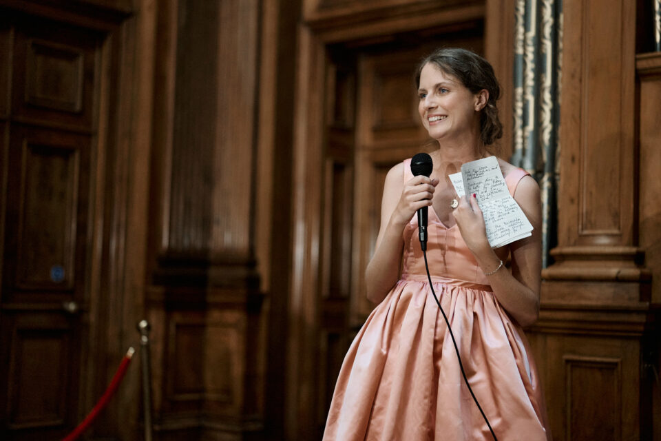 A lady in a pink dress is holding a microphone.