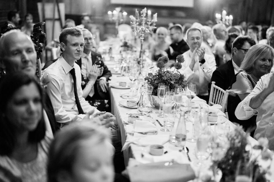 A black and white picture of people applauding at a wedding party.