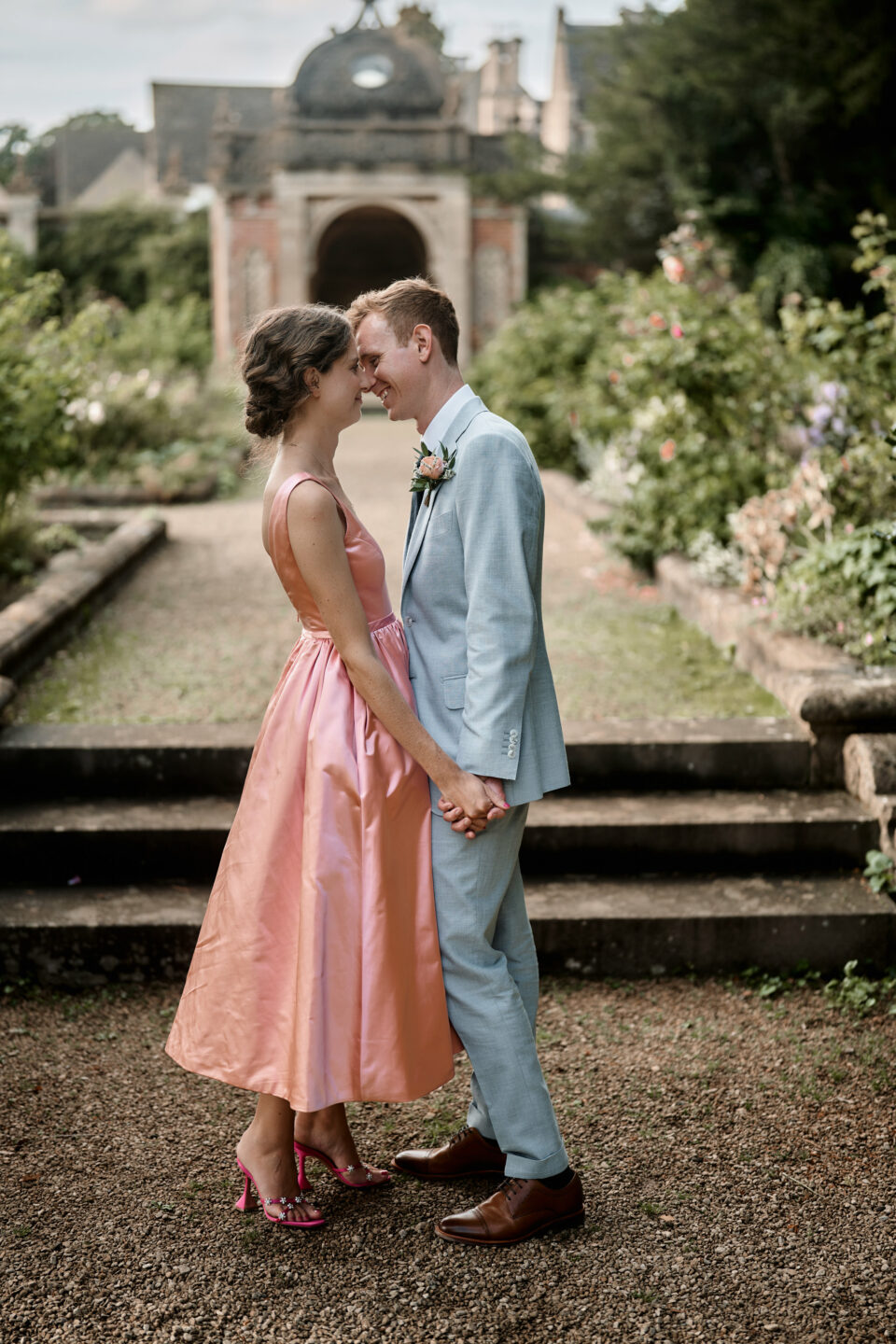 A couple getting married are sharing a kiss in front of a garden.