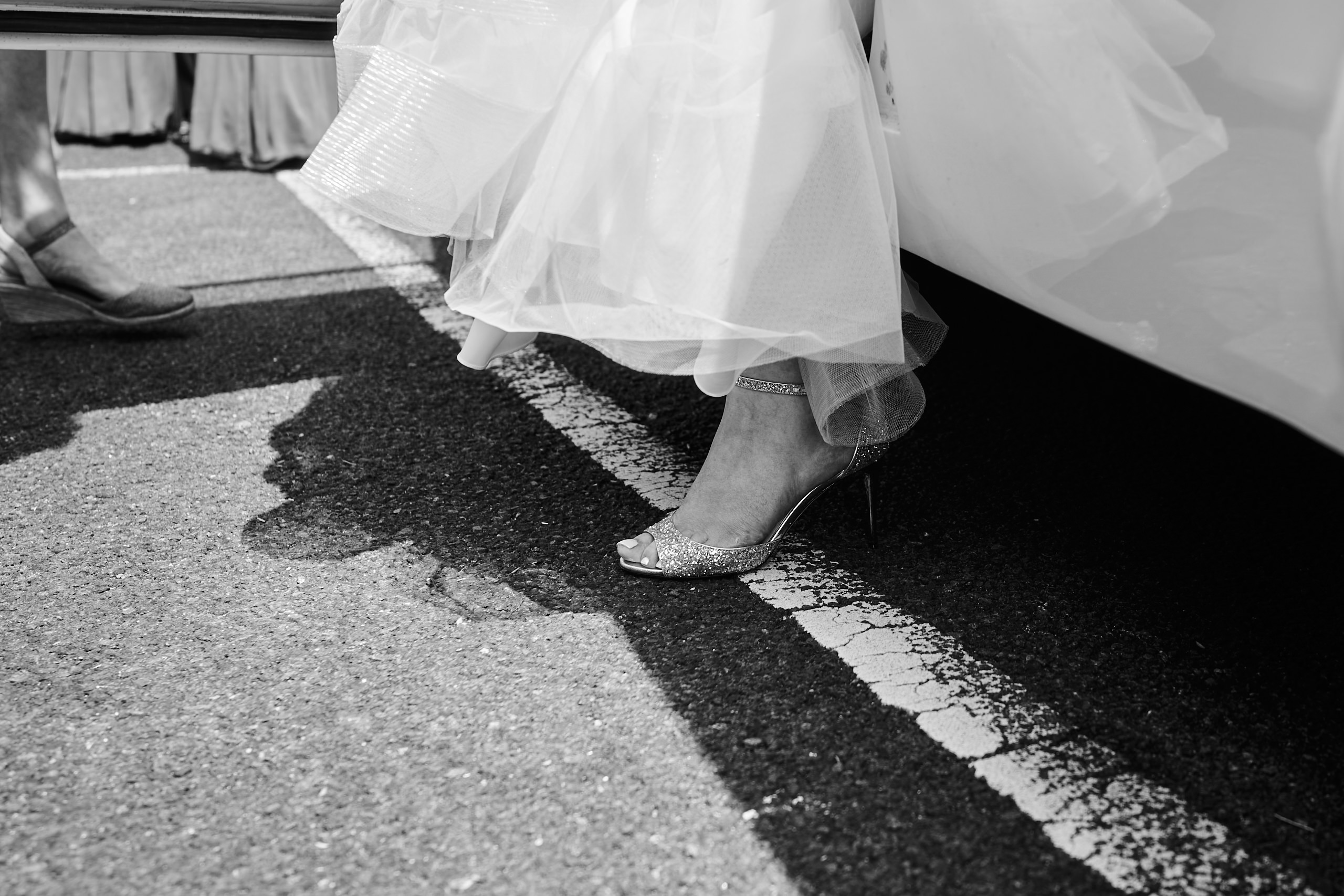 A bride is standing next to her wedding vehicle.