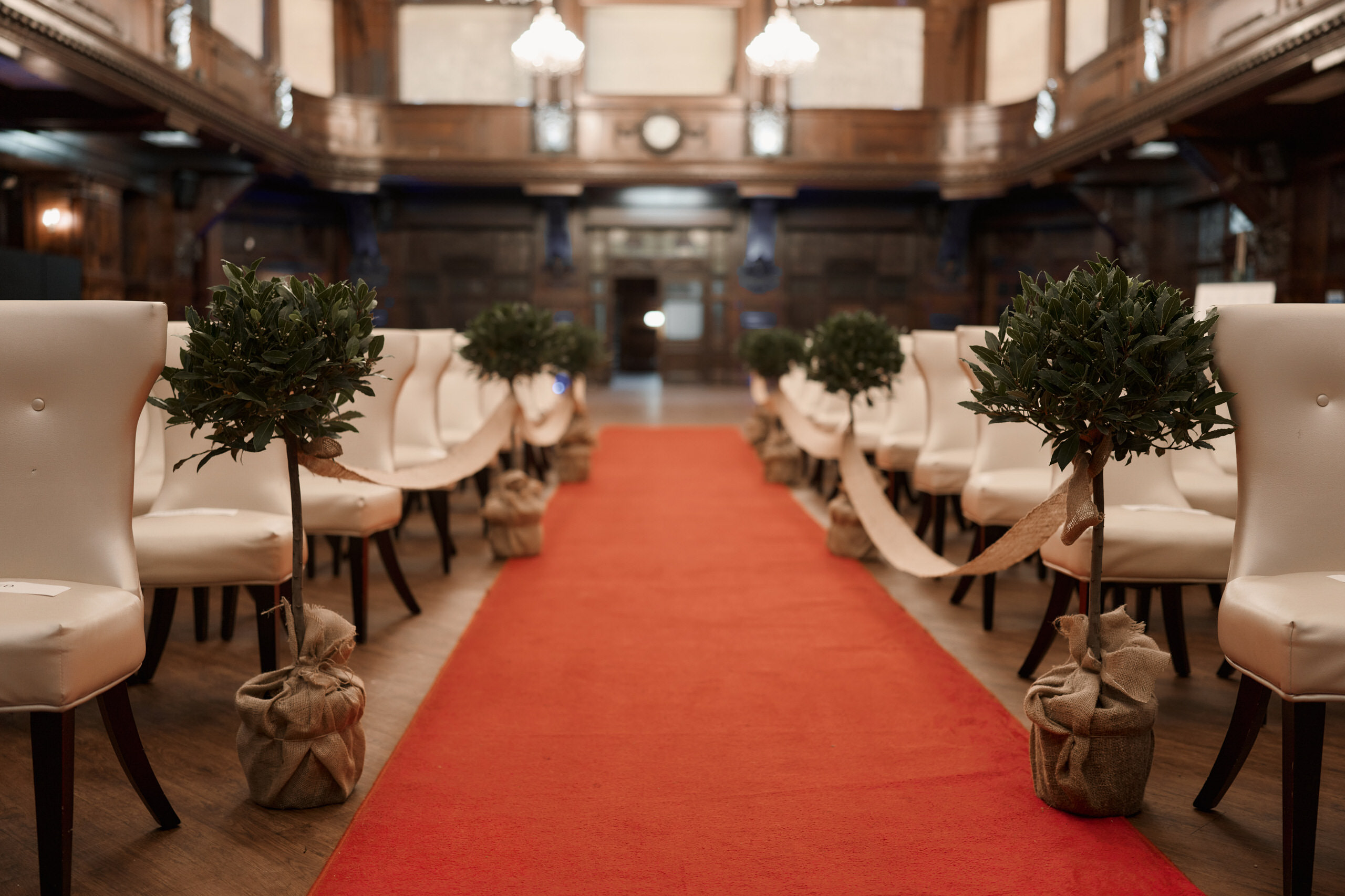 A big room with a red carpet where a wedding is taking place.
