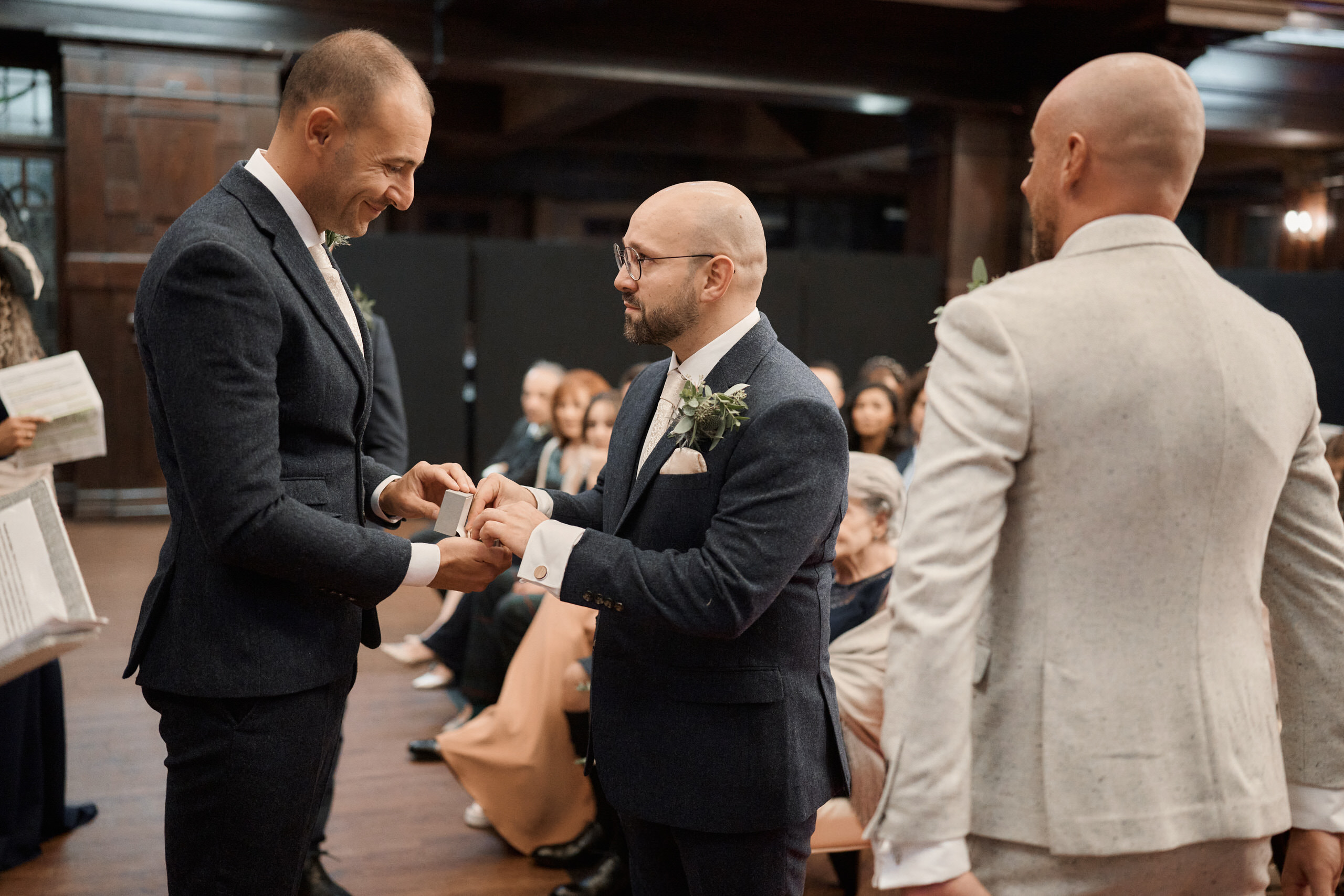 Two guys swapping rings at a wedding.