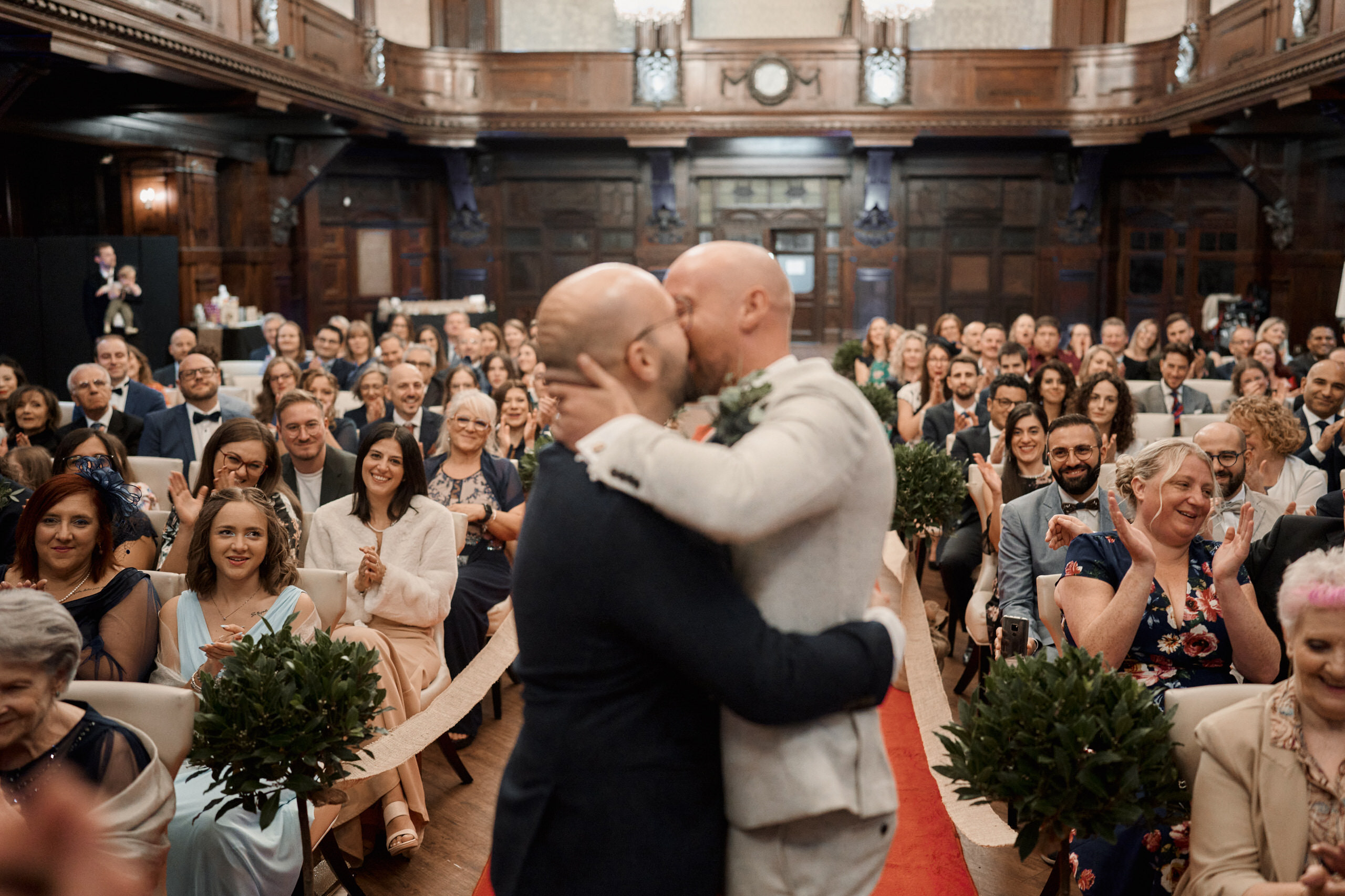 A couple is kissing in front of people at their wedding.