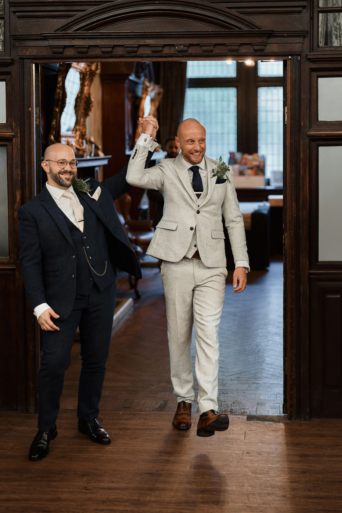 Two guys in suits stepping out from a door.