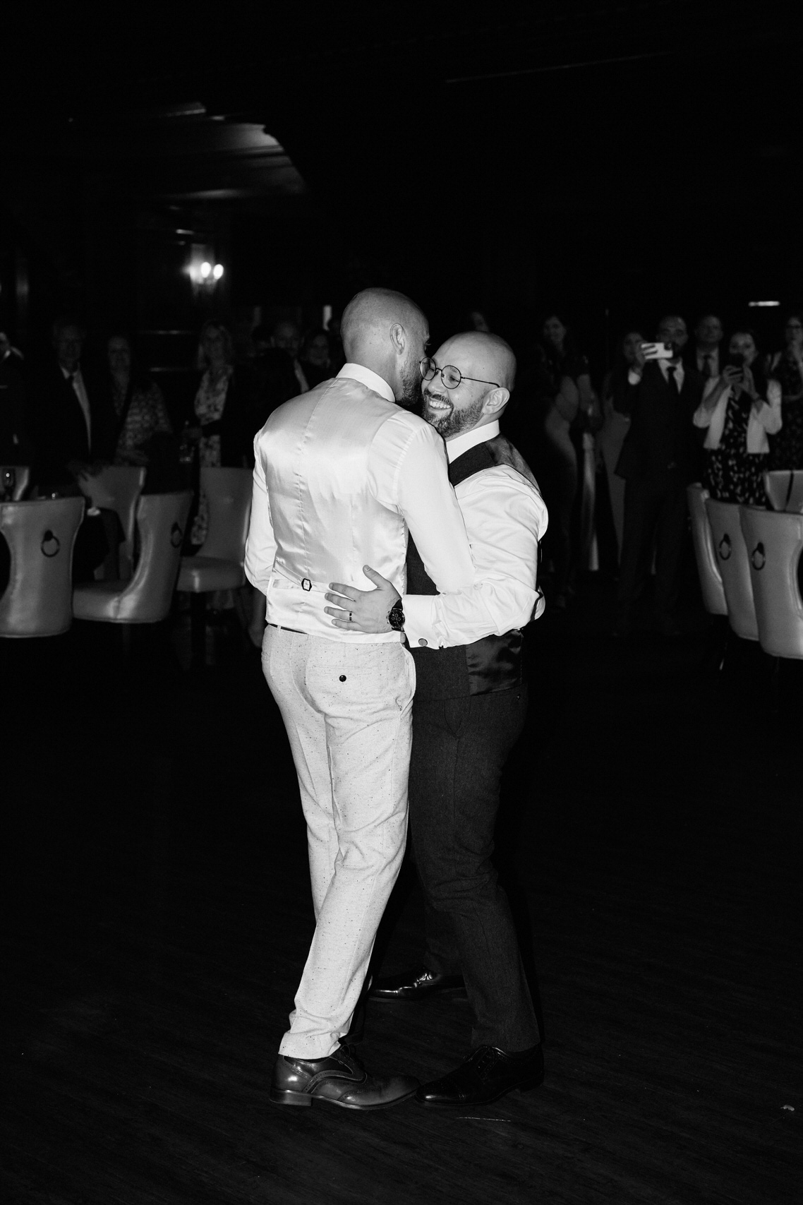 A black and white picture of two guys having a dance at a wedding.