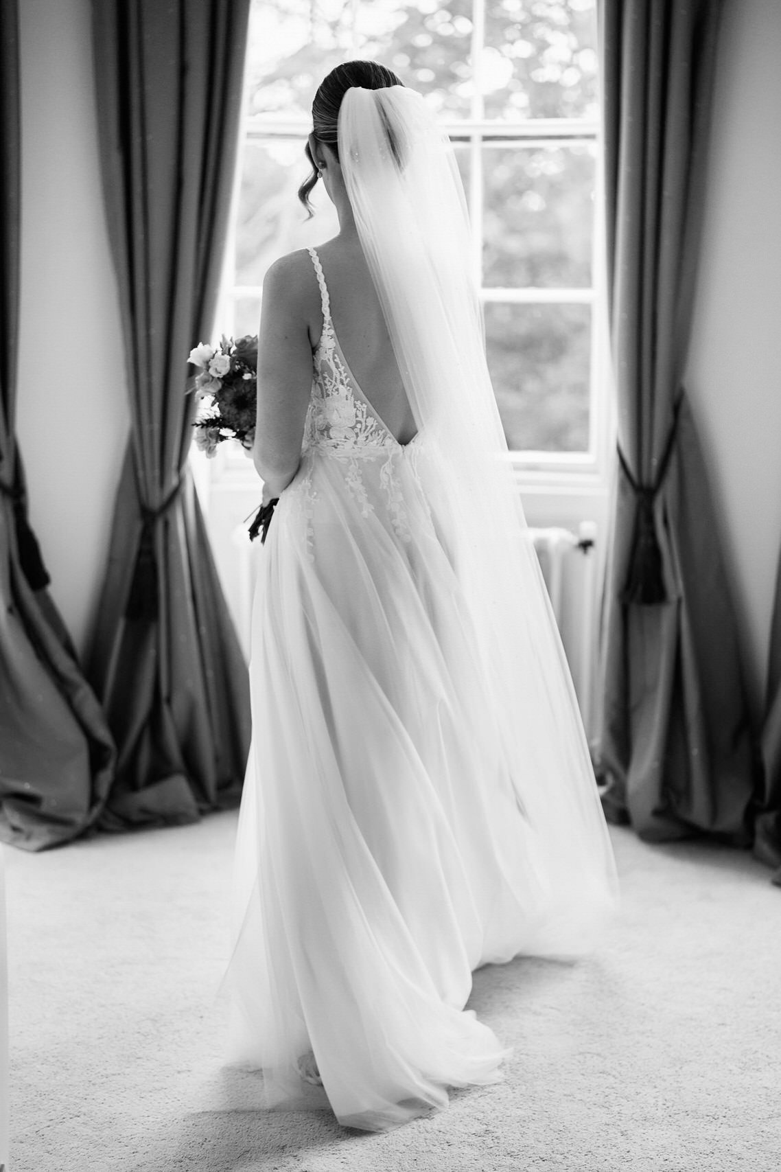 A bride in a wedding dress standing in front of a window.