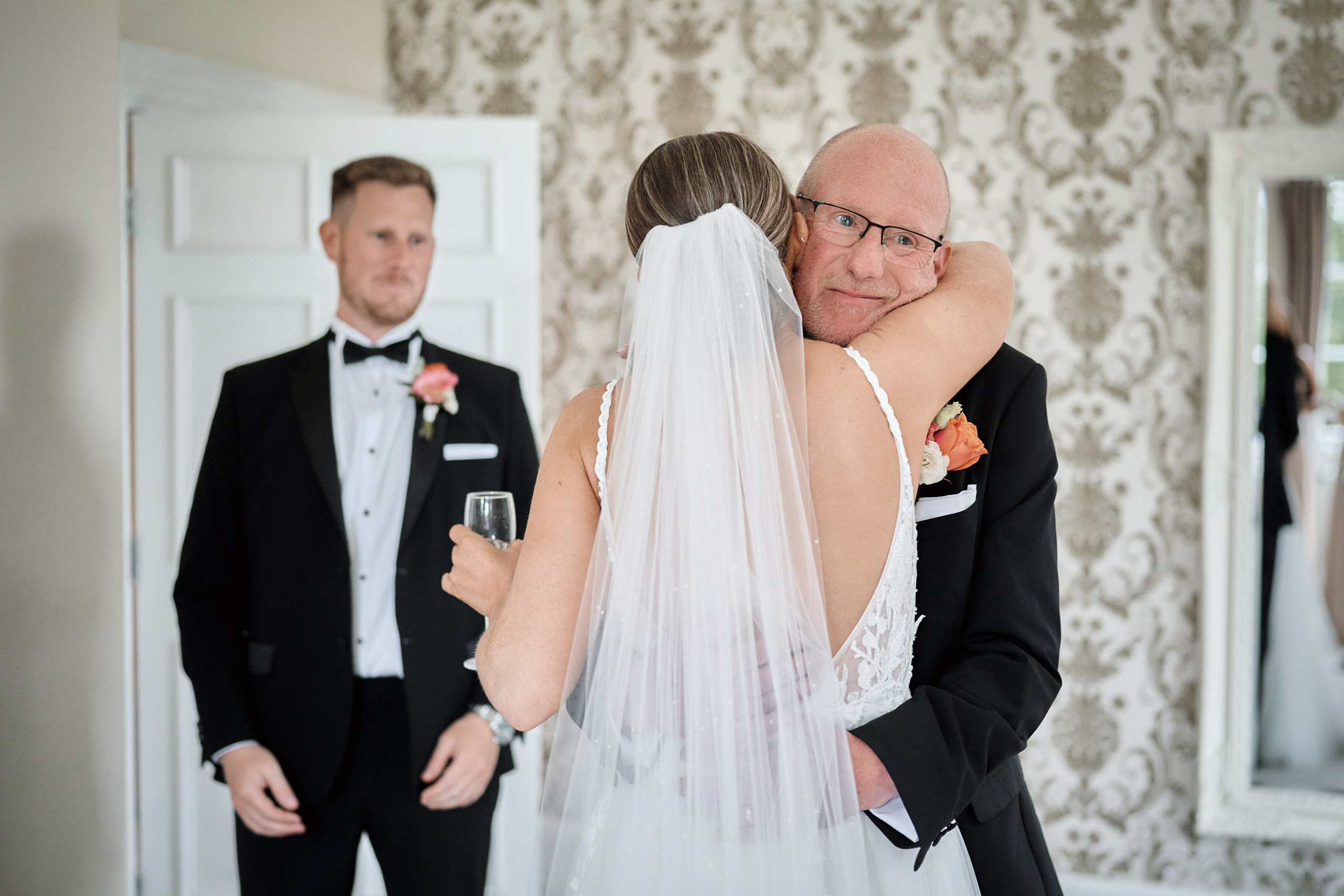 A bride and groom hugging in front of a mirror.