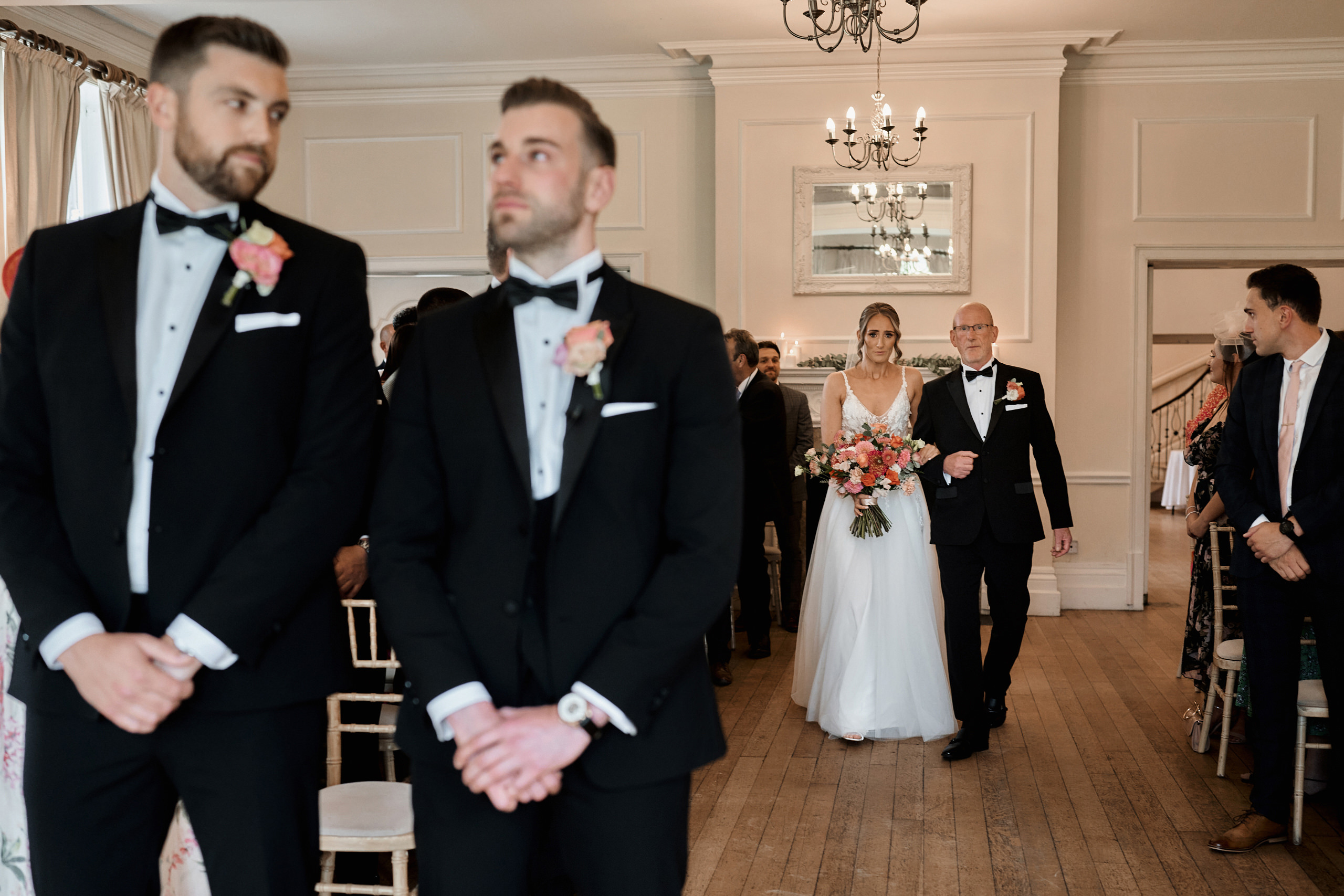 A bride and groom walking down the aisle in tuxedos.
