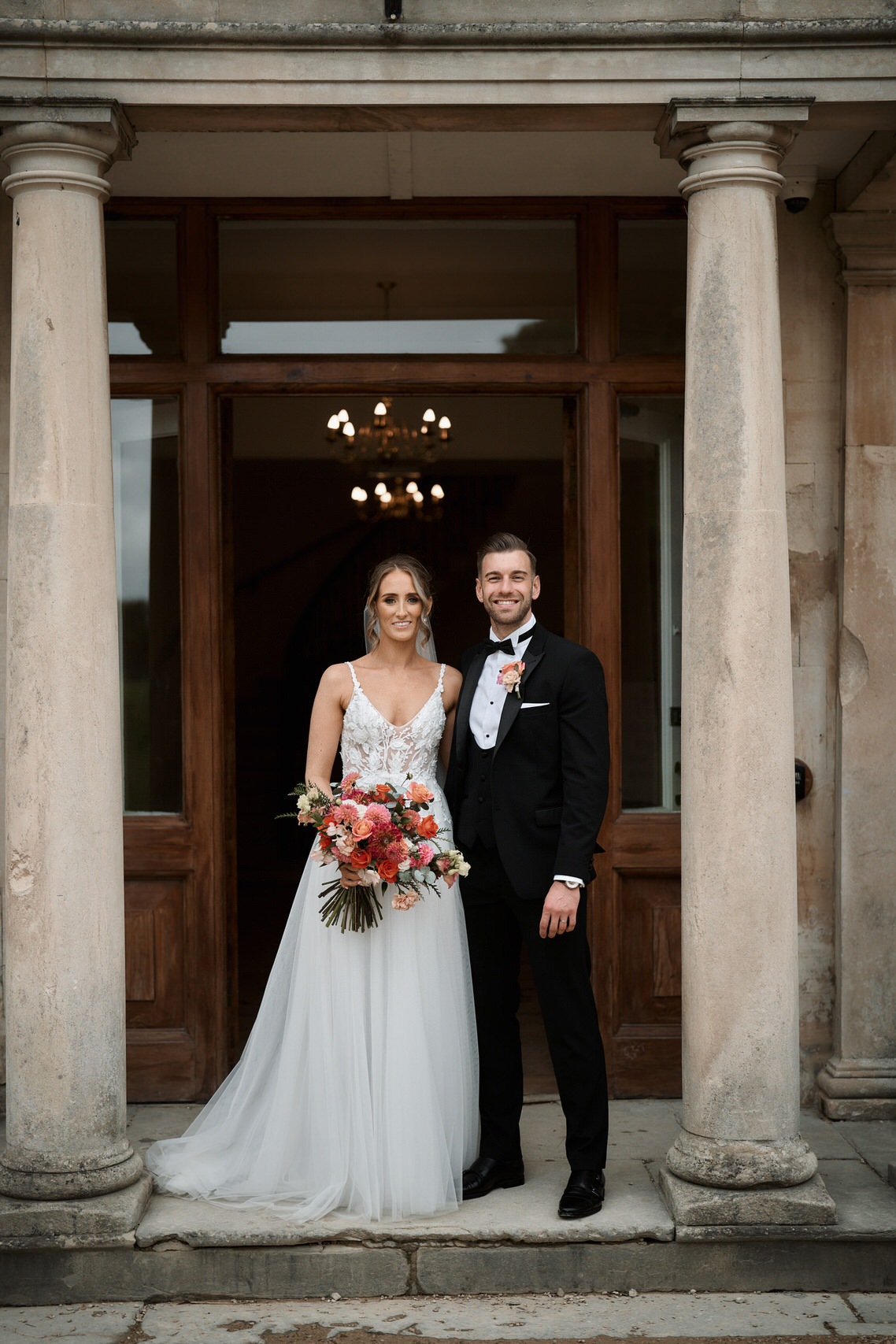 A bride and groom standing in front of an ornate doorway.