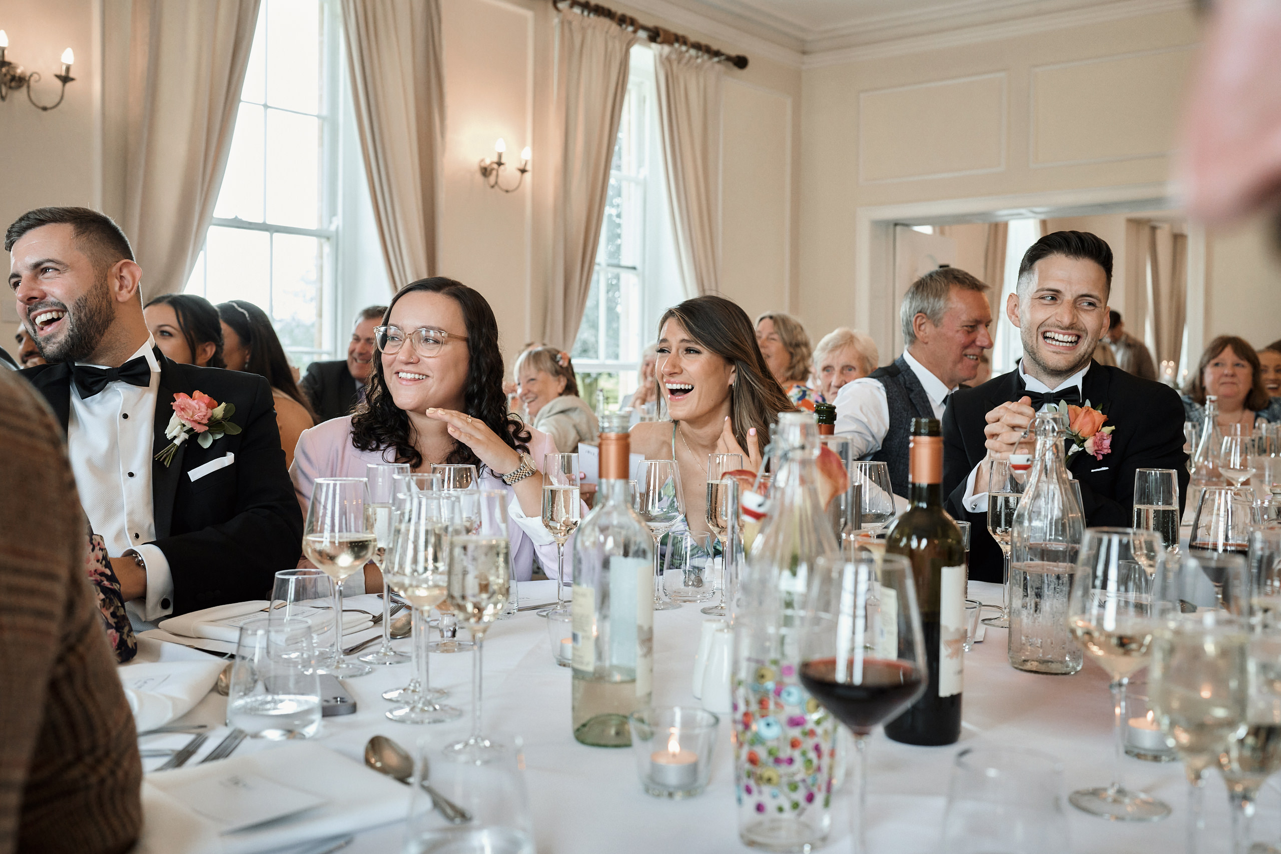 A group of people laughing at a wedding reception.