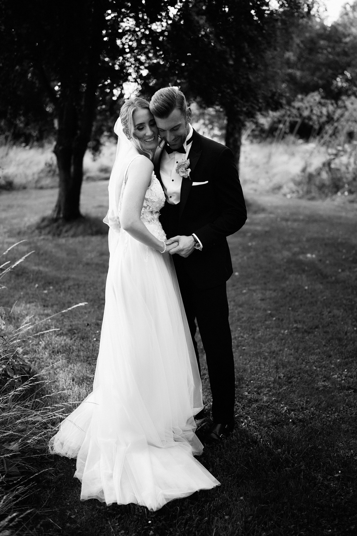 A bride and groom embracing in the grass.