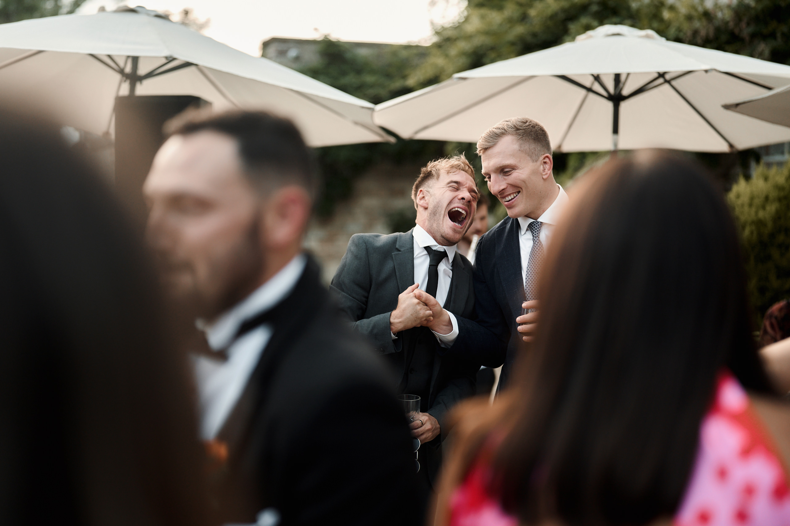 A group of men laughing at a wedding reception.