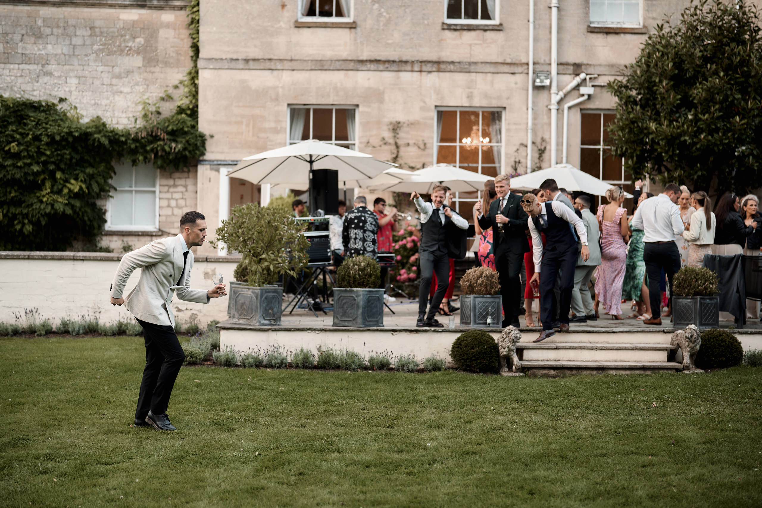A man in a suit is throwing a frisbee in front of a house.