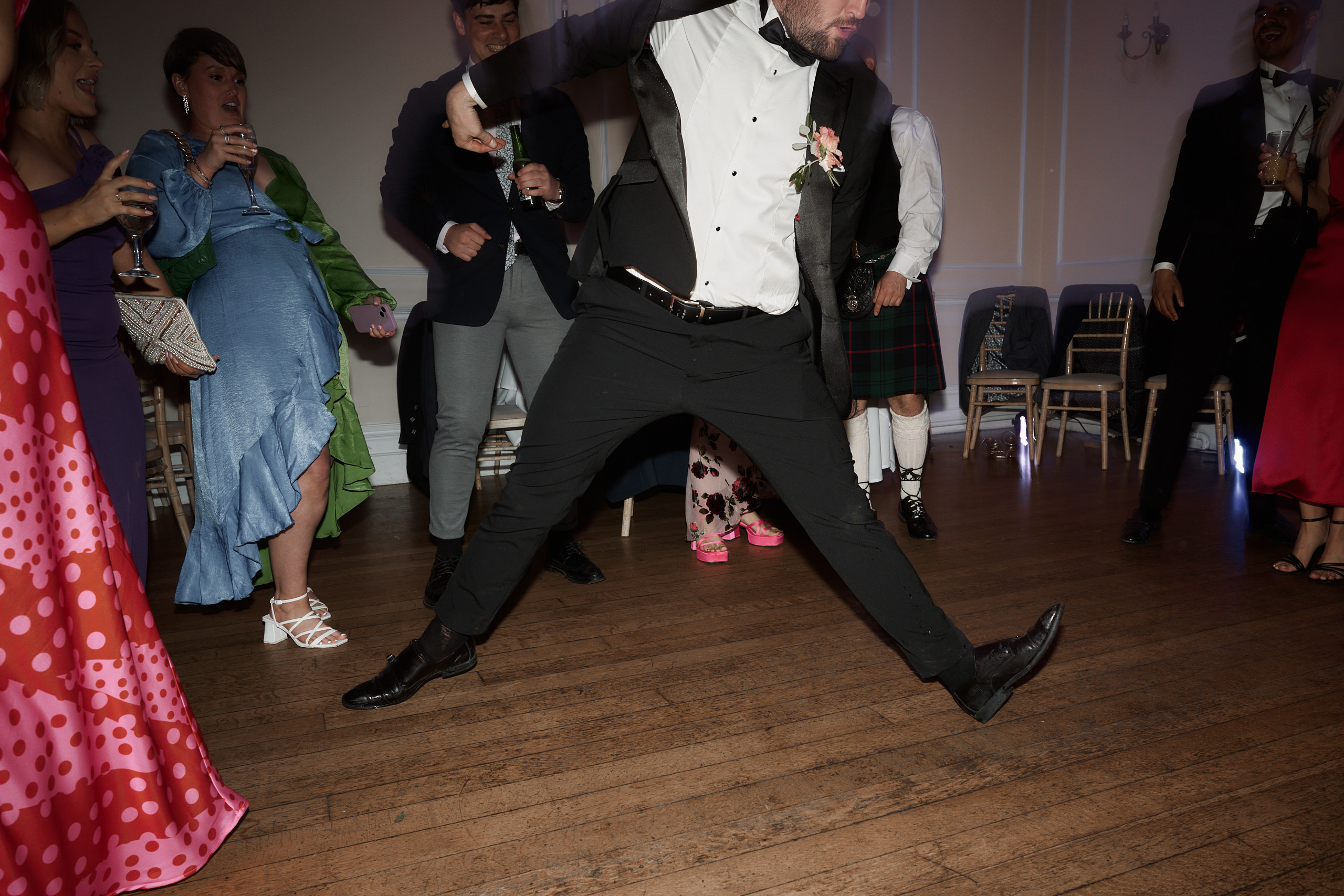 A man in a tuxedo dancing at a wedding.