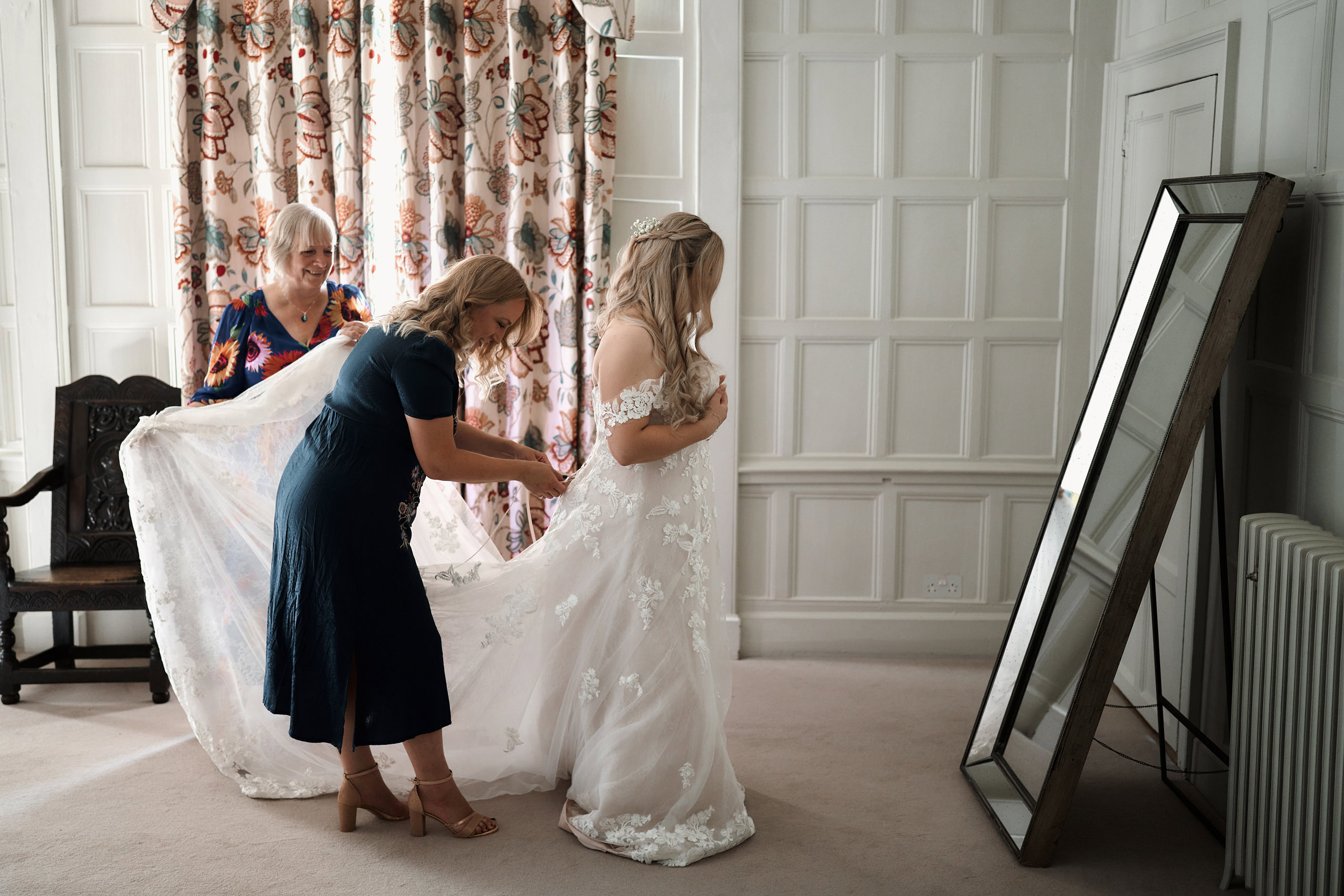A bride is preparing for her wedding in a room that has a mirror.