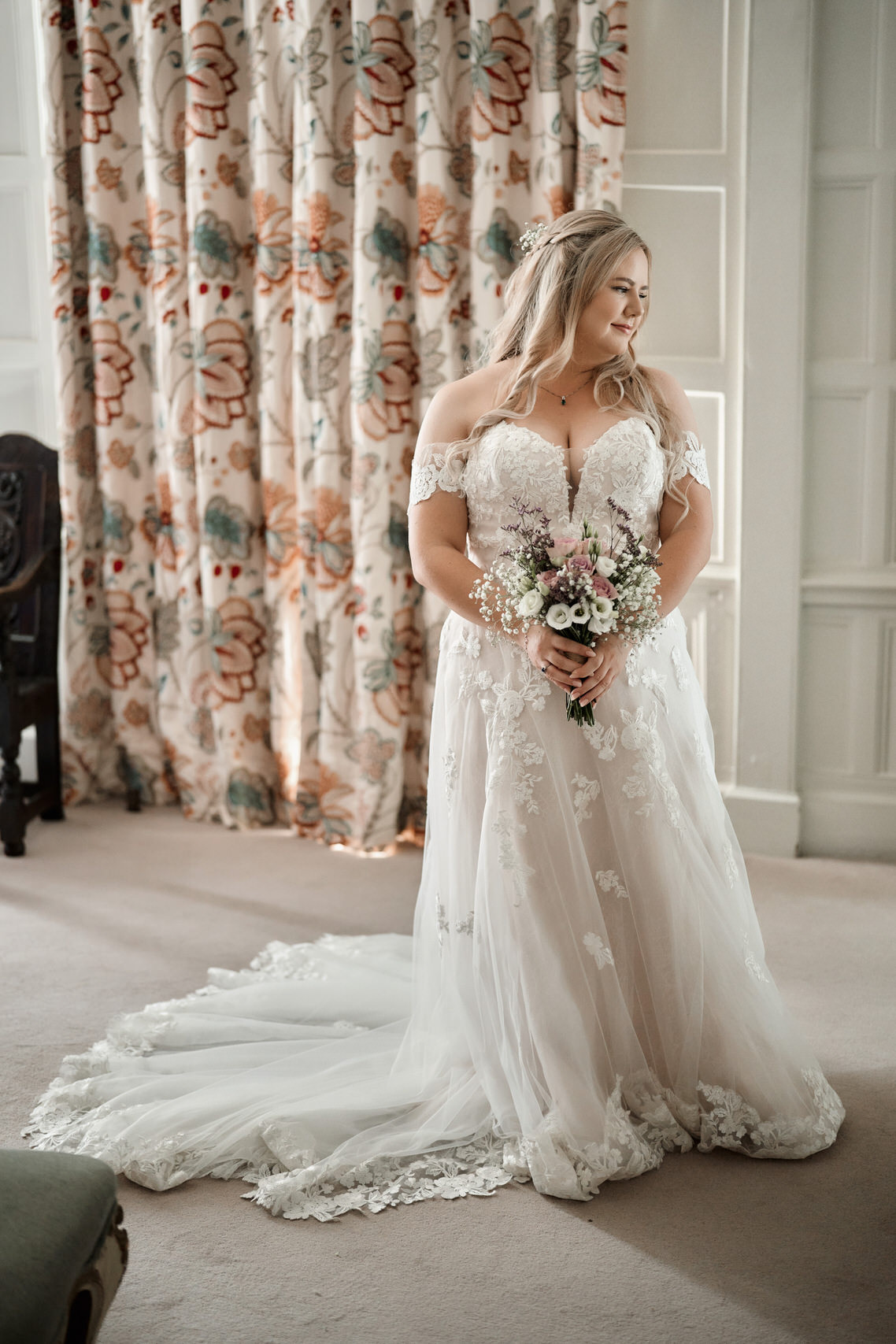 A woman in a wedding gown is standing in a room.