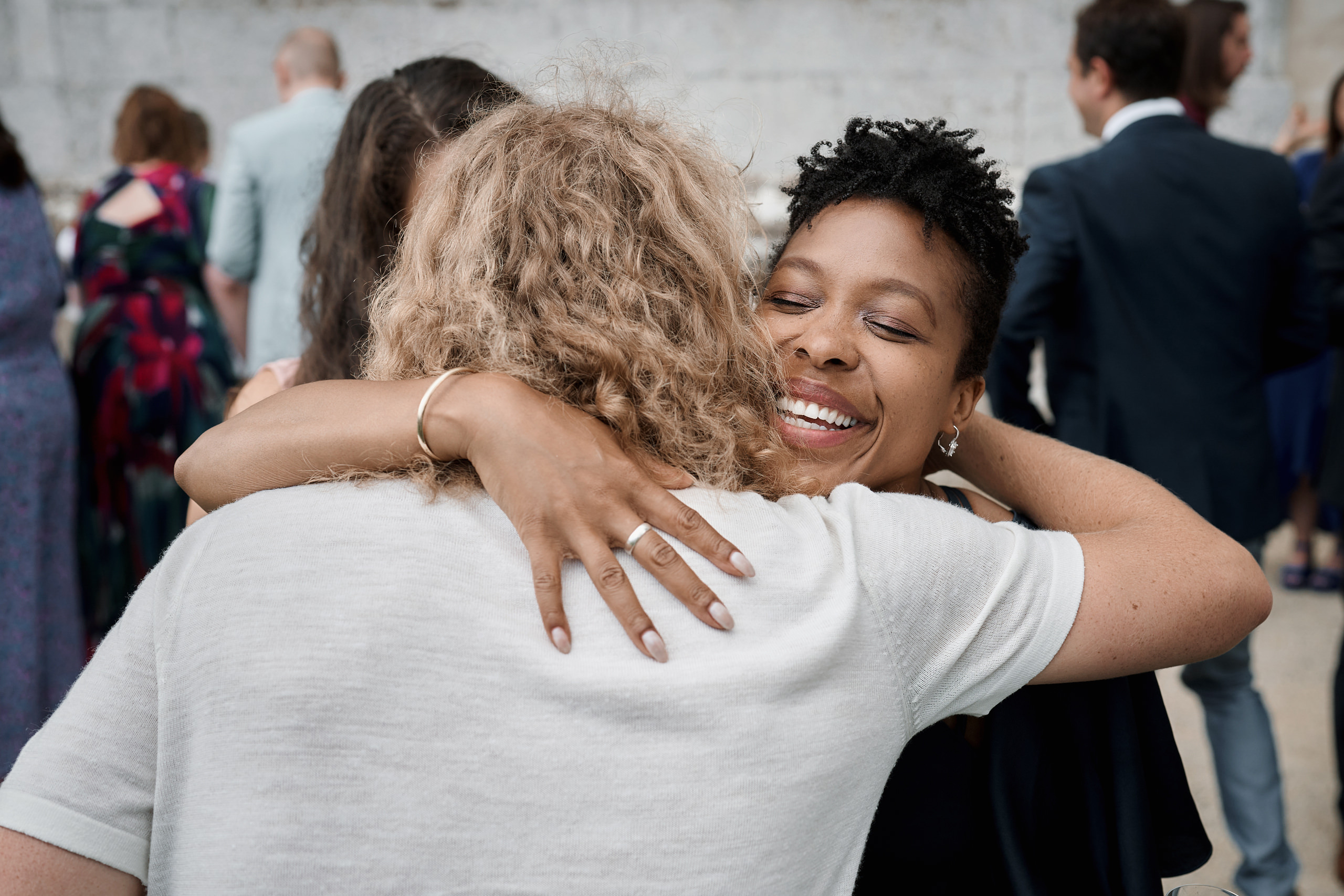 A lady is giving another lady a hug at some gathering.