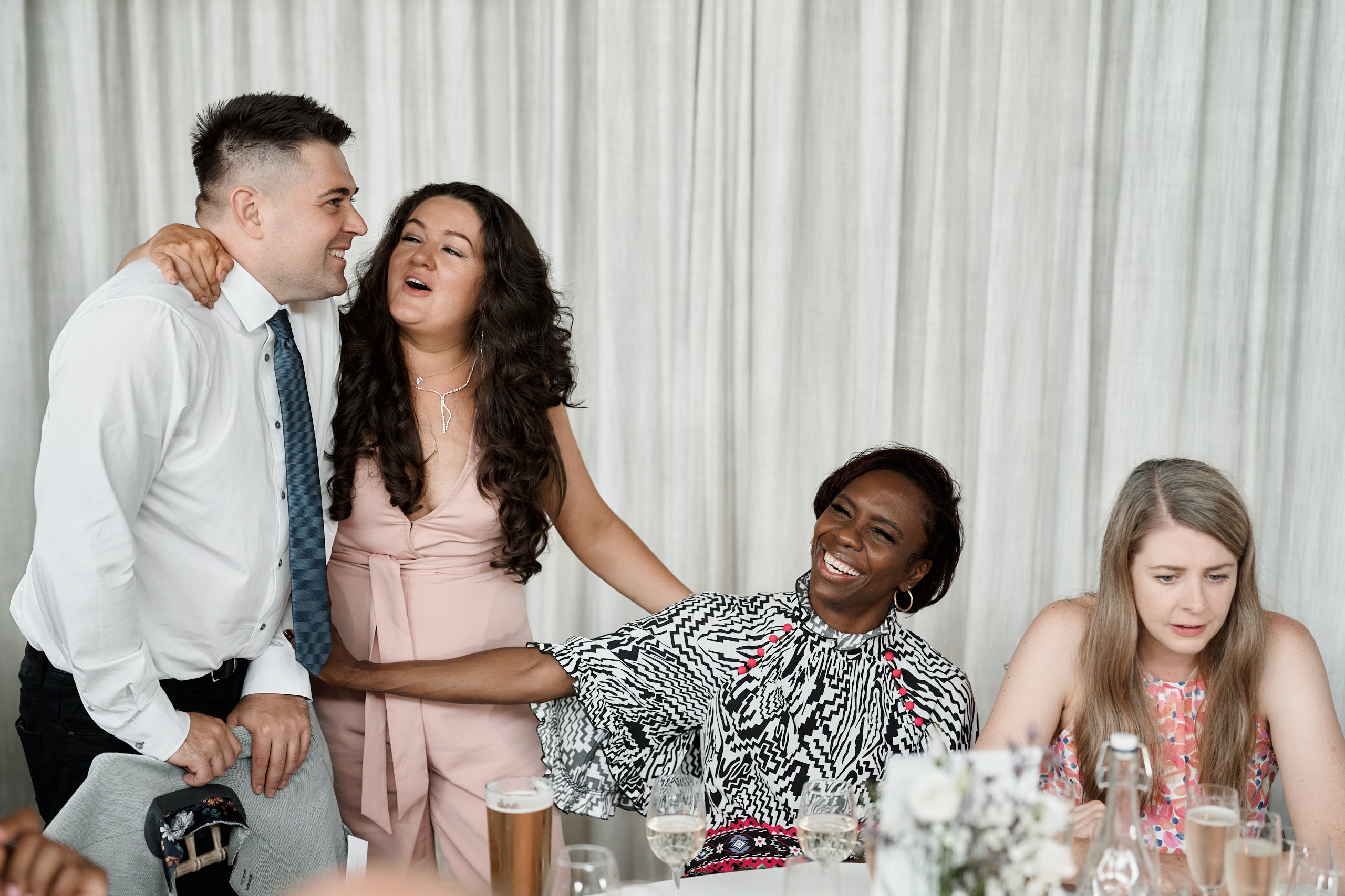 Some folks cracking up at a wedding party.