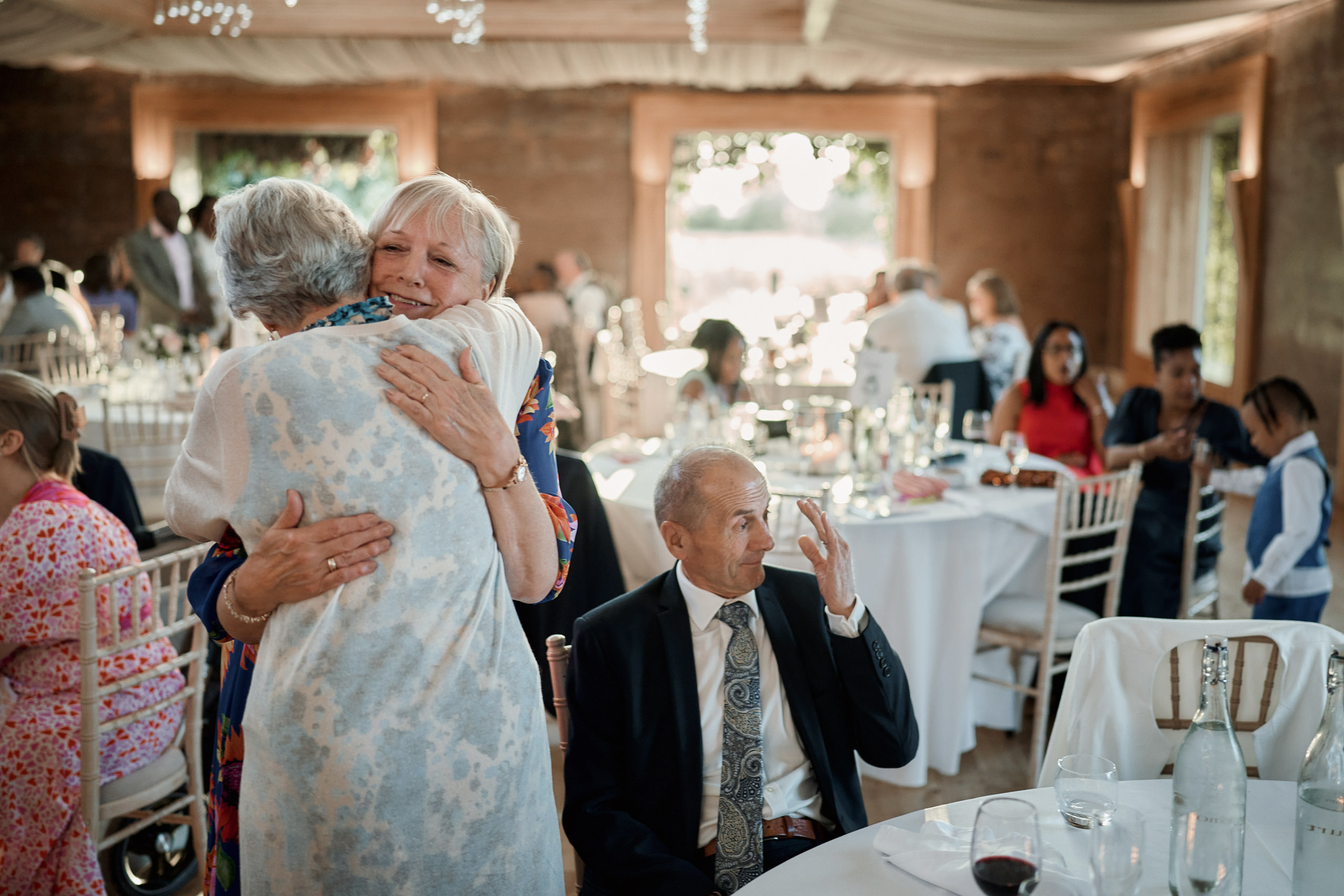 A woman is giving an older lady a hug at a wedding party.