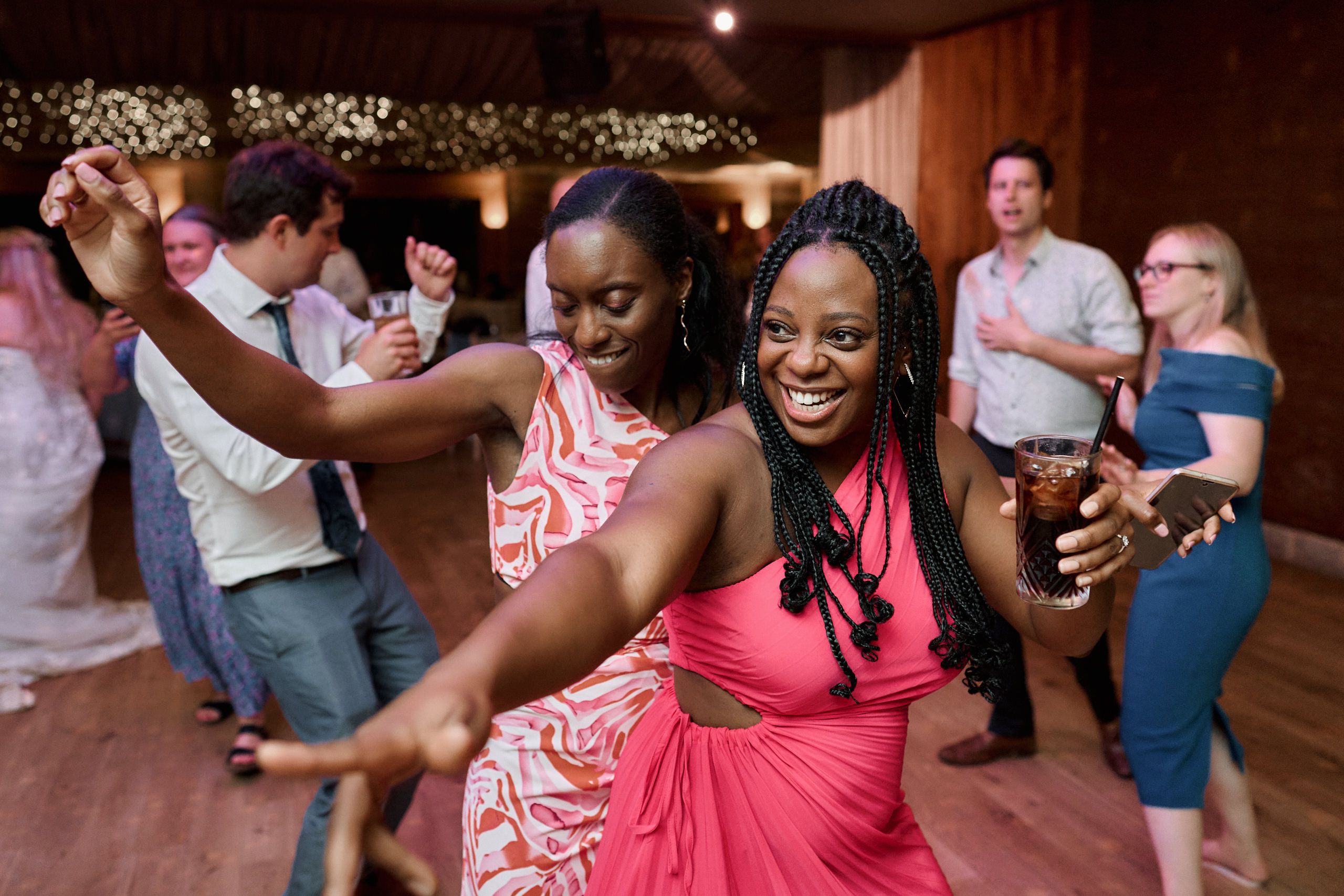 Two ladies are busting some moves on the dance floor at a wedding.