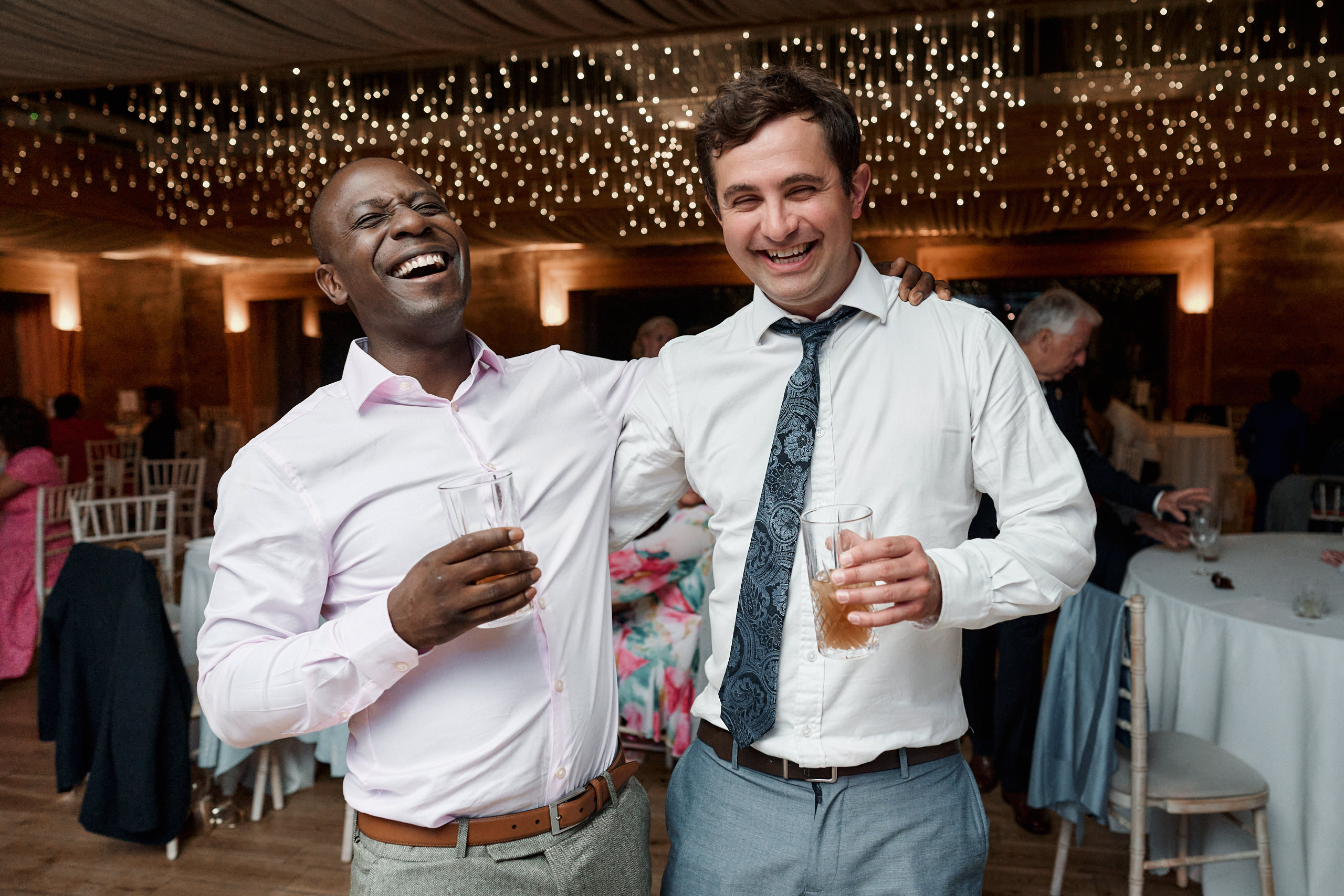 Two guys cracking up at a wedding party.