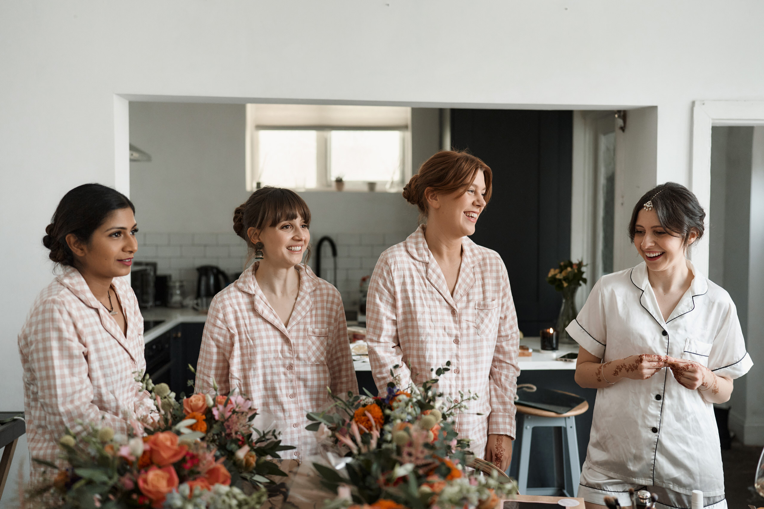 A bunch of bridesmaids in pajamas hanging out around a table.