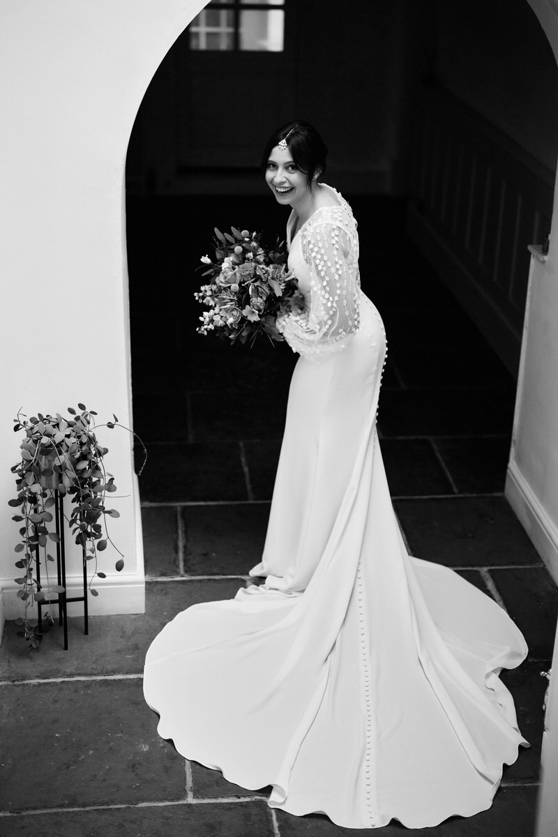 A woman in a wedding dress is standing under an arch.