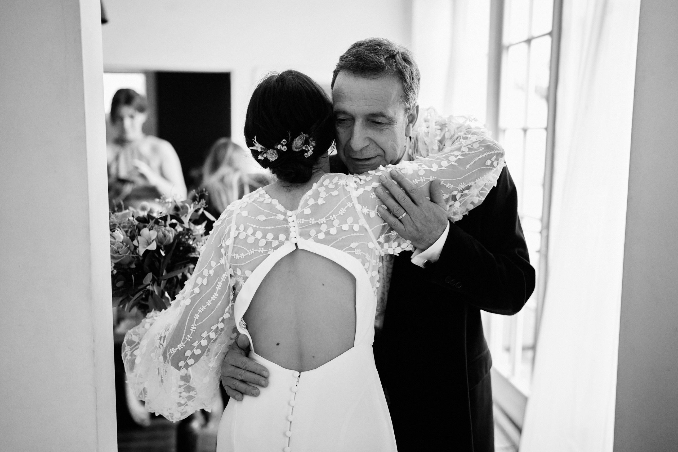 A black and white picture of a bride giving her dad a hug.