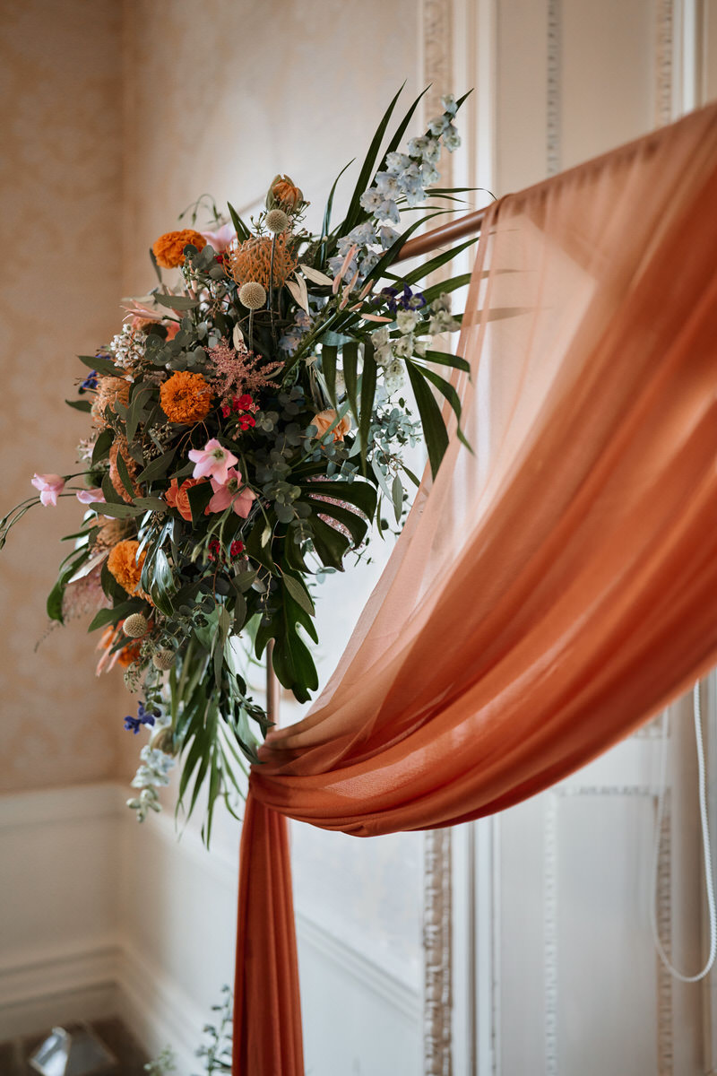 An arch for a wedding is covered in orange flowers.