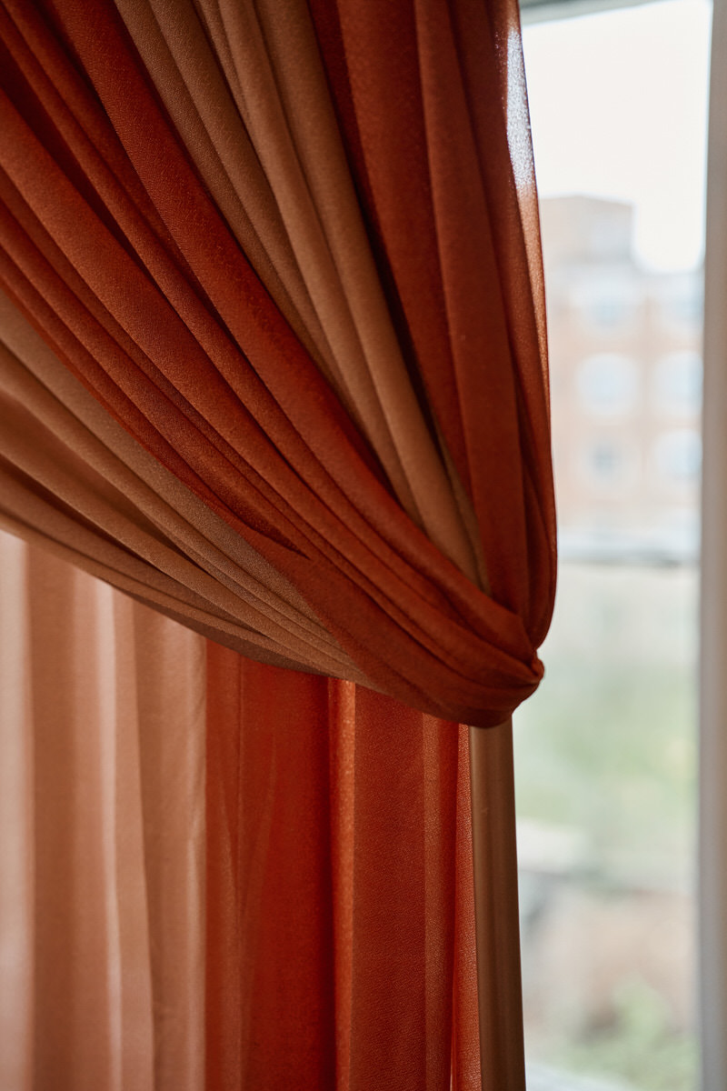 A zoomed-in view of a curtain next to a window in a room.