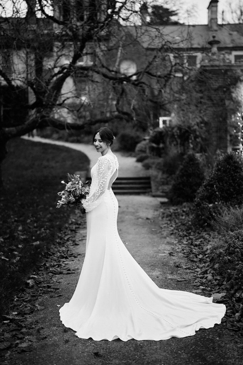 A black and white picture of a bride standing in a park.