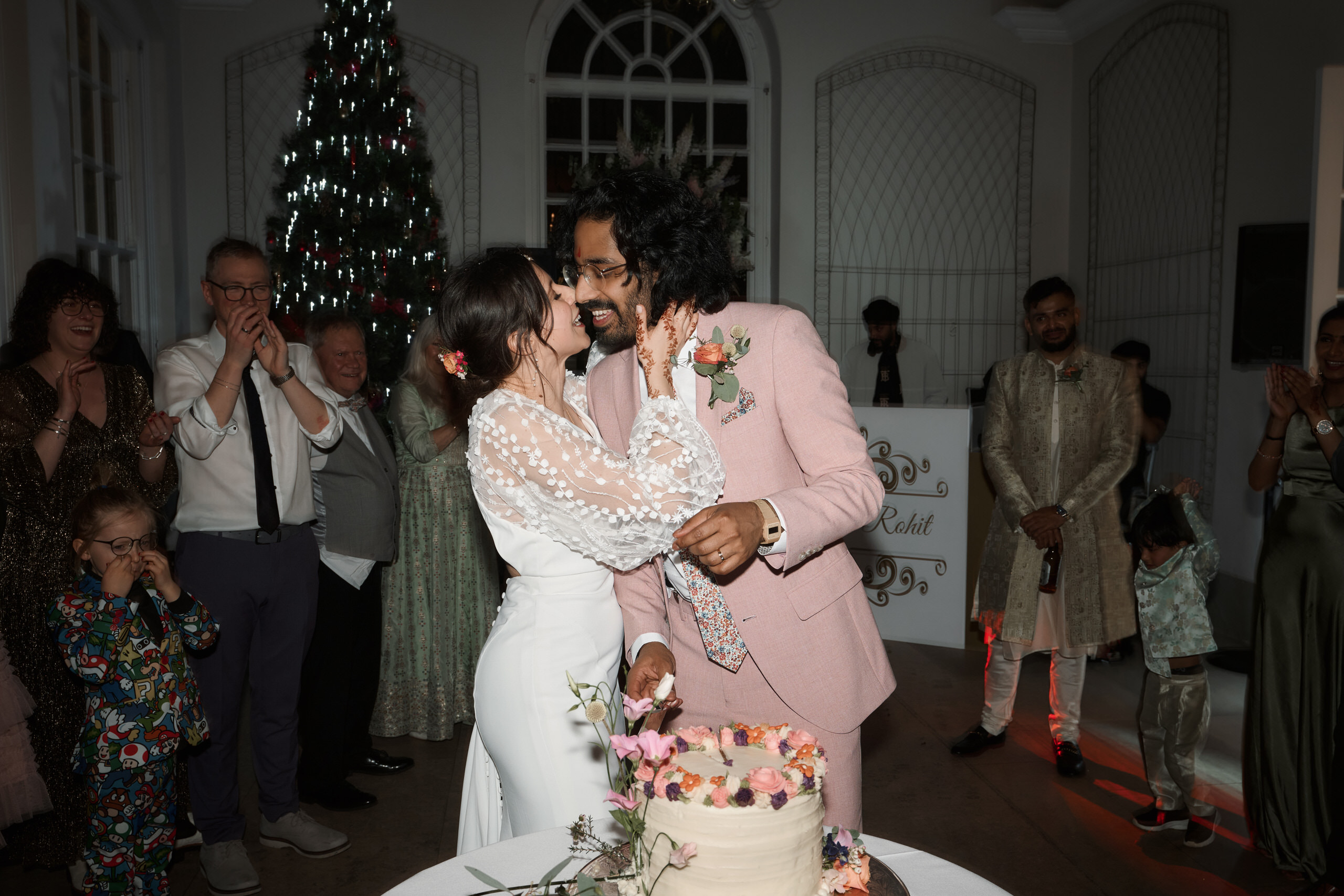 A couple getting married is kissing in front of their wedding cake.