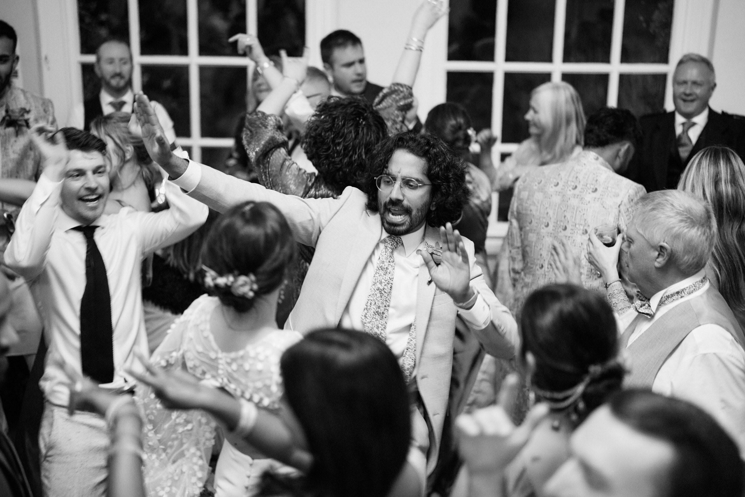 A grayscale picture showing a bunch of folks dancing at a wedding.
