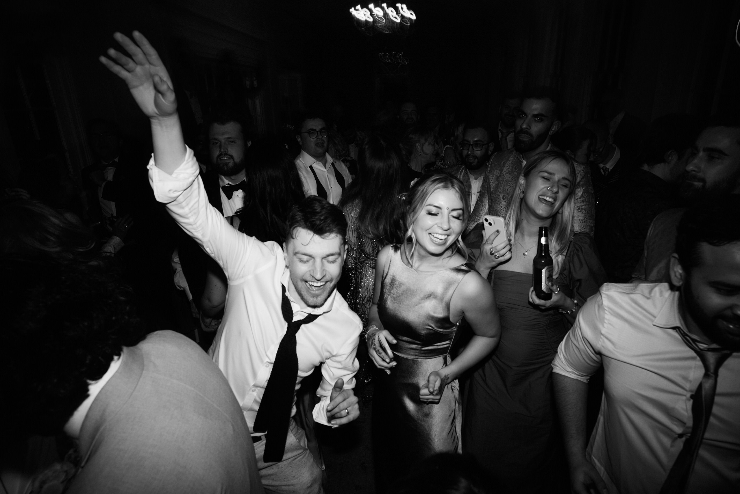 A picture in black and white showing people dancing at a party.