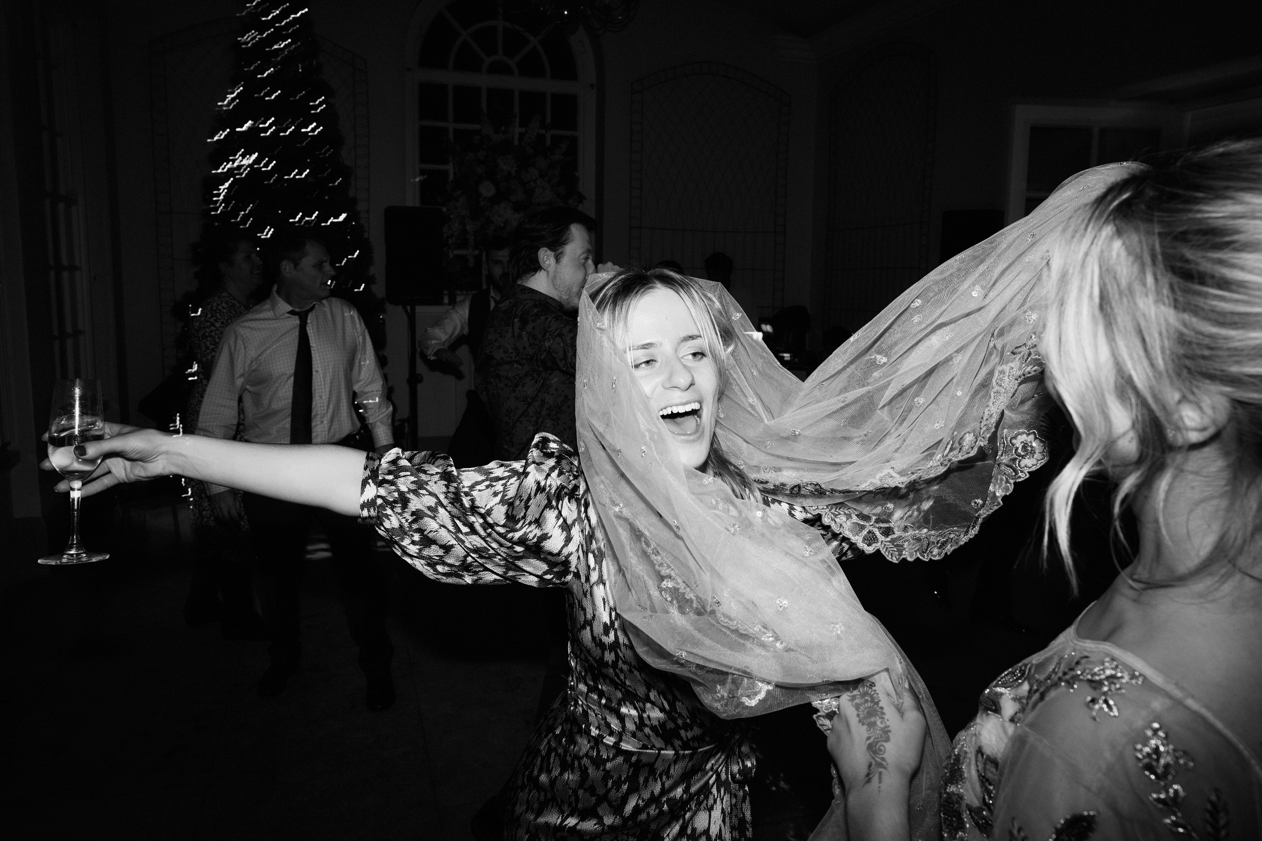Two women are wearing veils and dancing at a party.