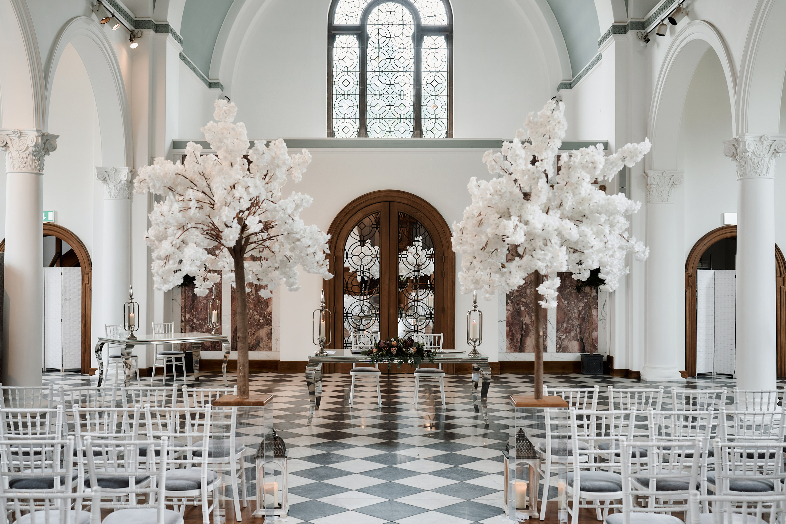 A wedding is happening in a church with white chairs and trees.