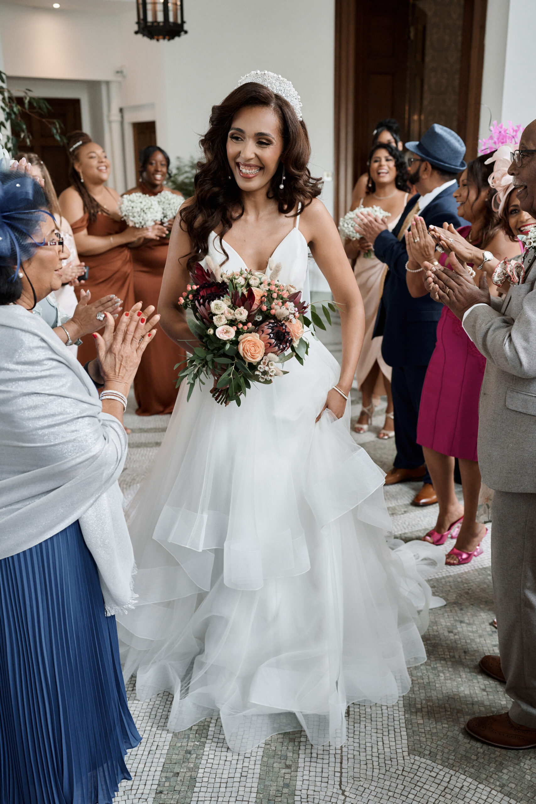 A Bride in a white outfit carrying a bunch of flowers.