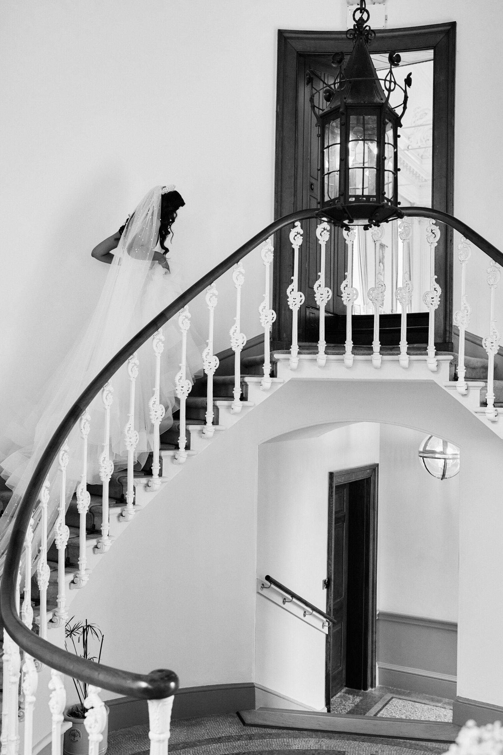 A black and white picture shows a bride going down the stairs.