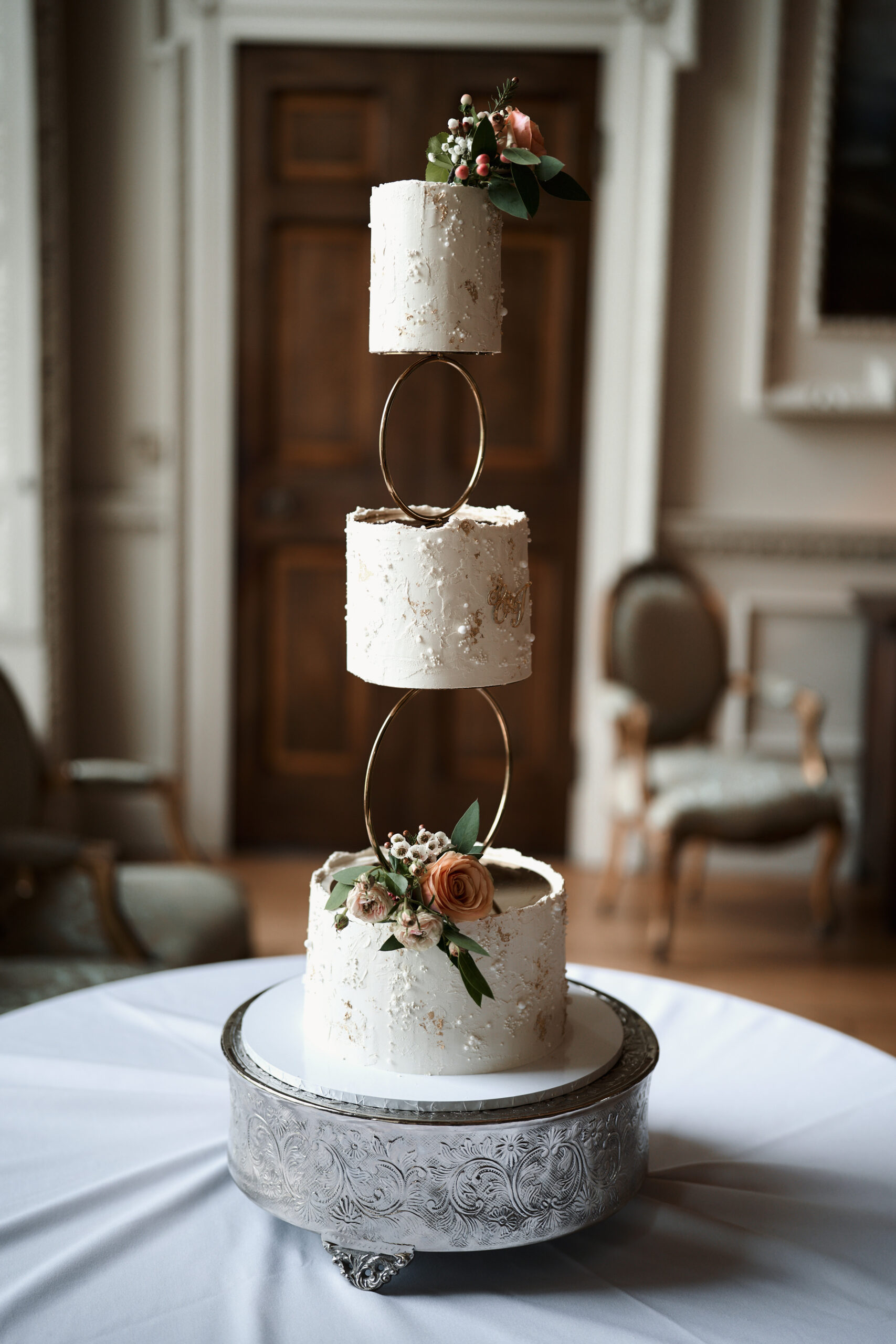 There's a three-layer wedding cake on a table in a room.
