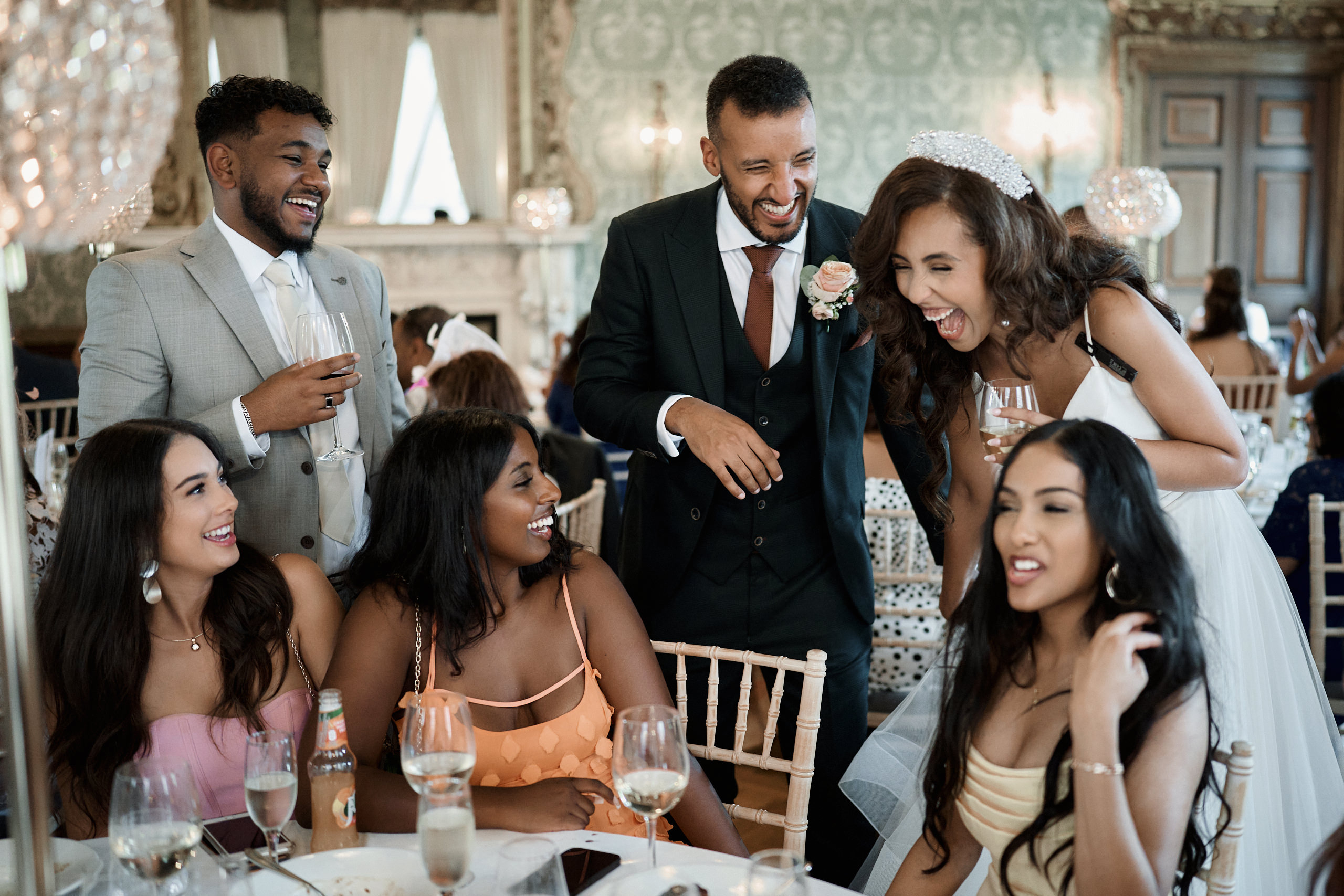 A bunch of people cracking up at a wedding party.